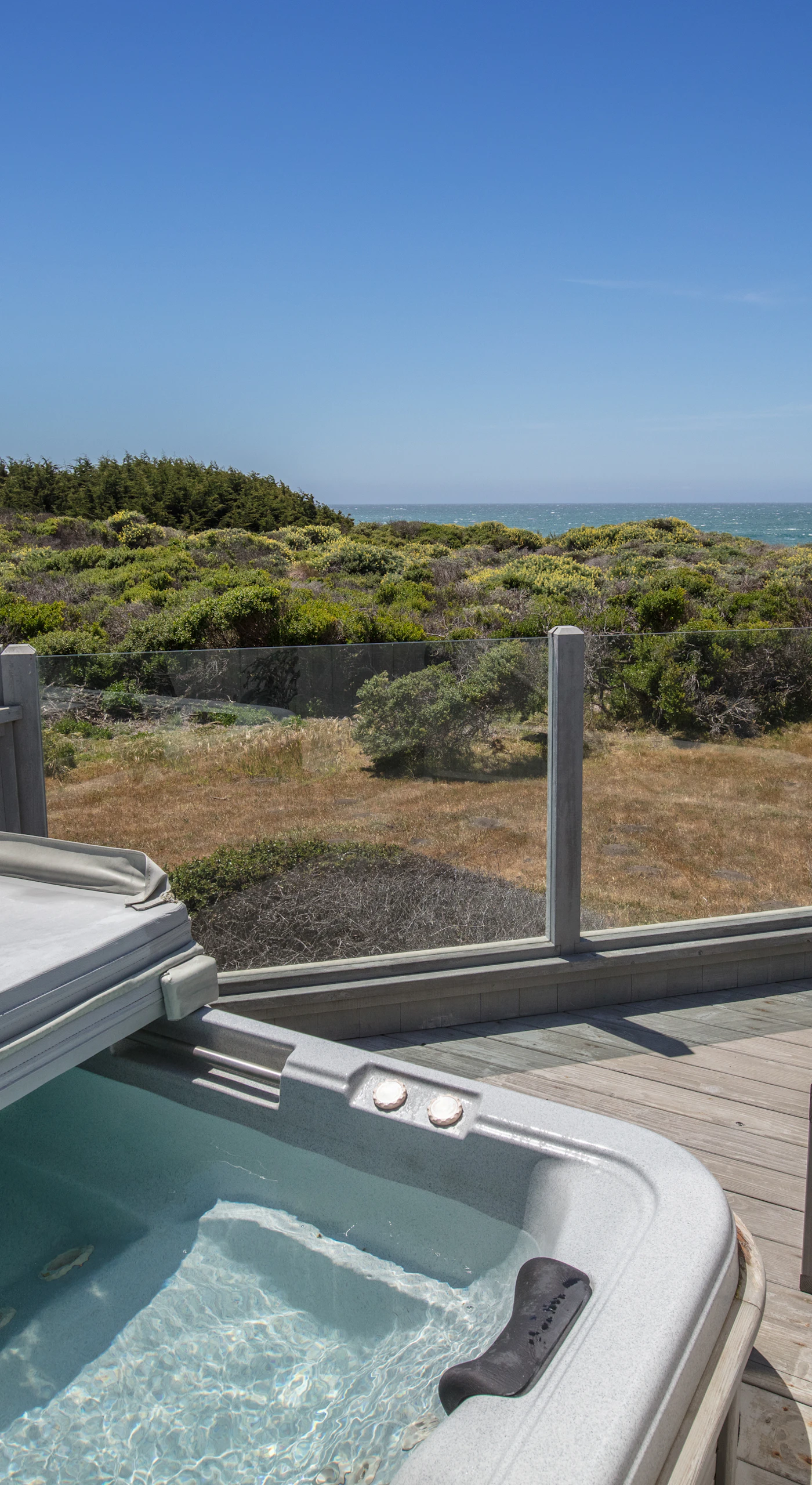 Soak in your private hot tub, surrounded by nature, as you watch waves crash against the shore; pure relaxation awaits.
