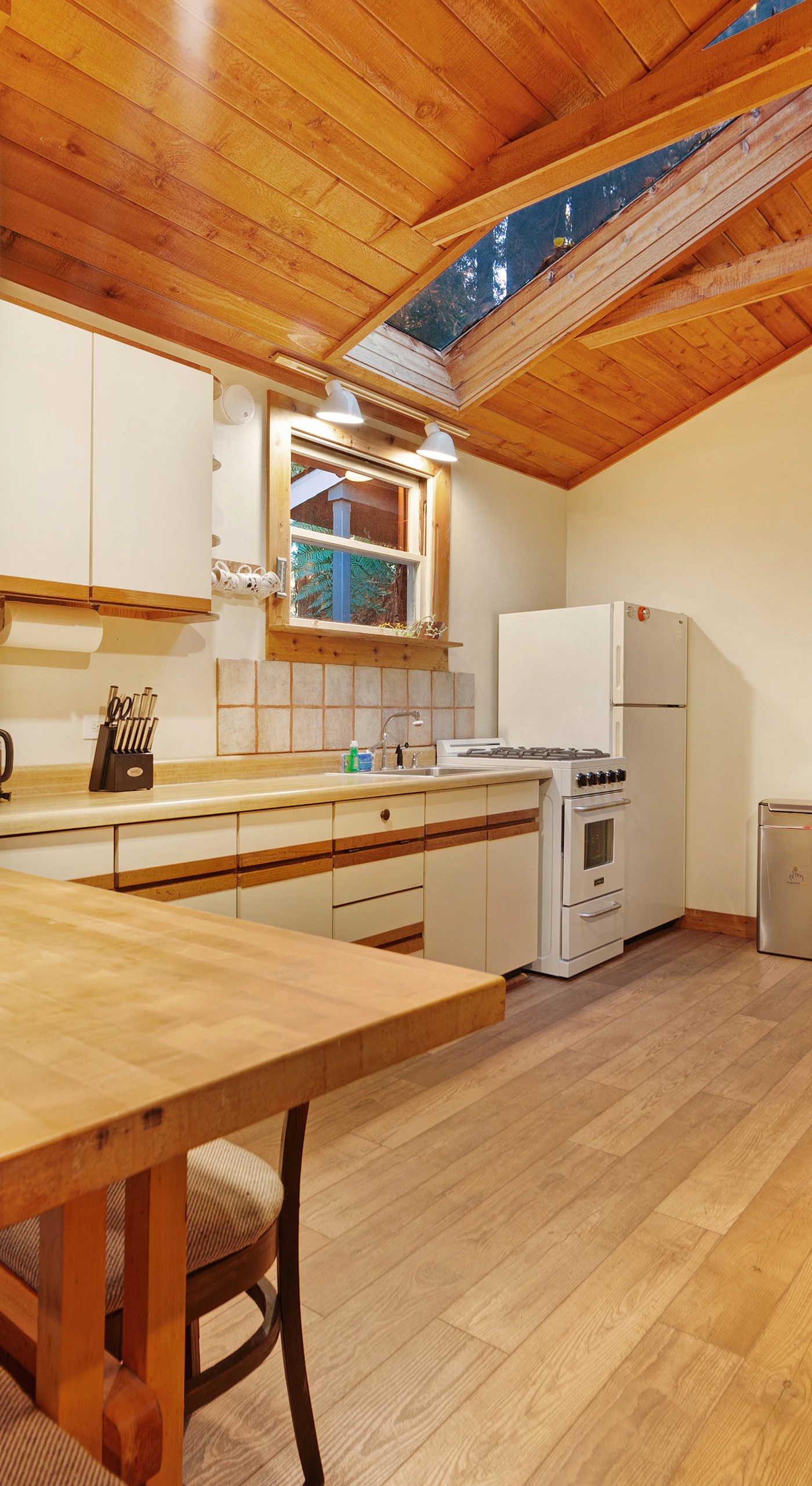 Bright natural light pours through the skylight onto your generous kitchen counter space beneath warm wood ceilings.