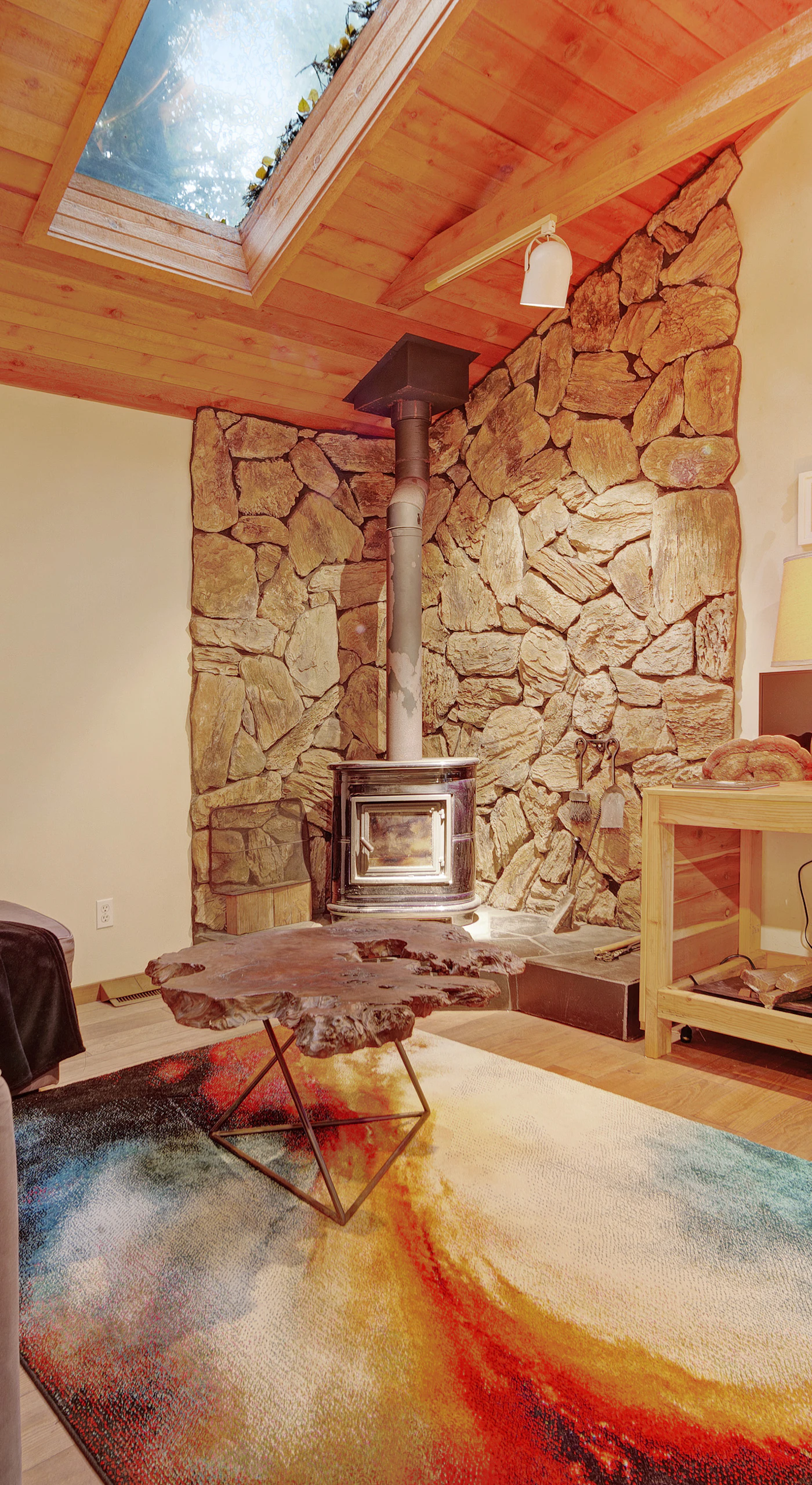 Cozy up by your wood-burning fireplace beneath soaring vaulted ceilings and a skylight that fills this redwood retreat with natural light.