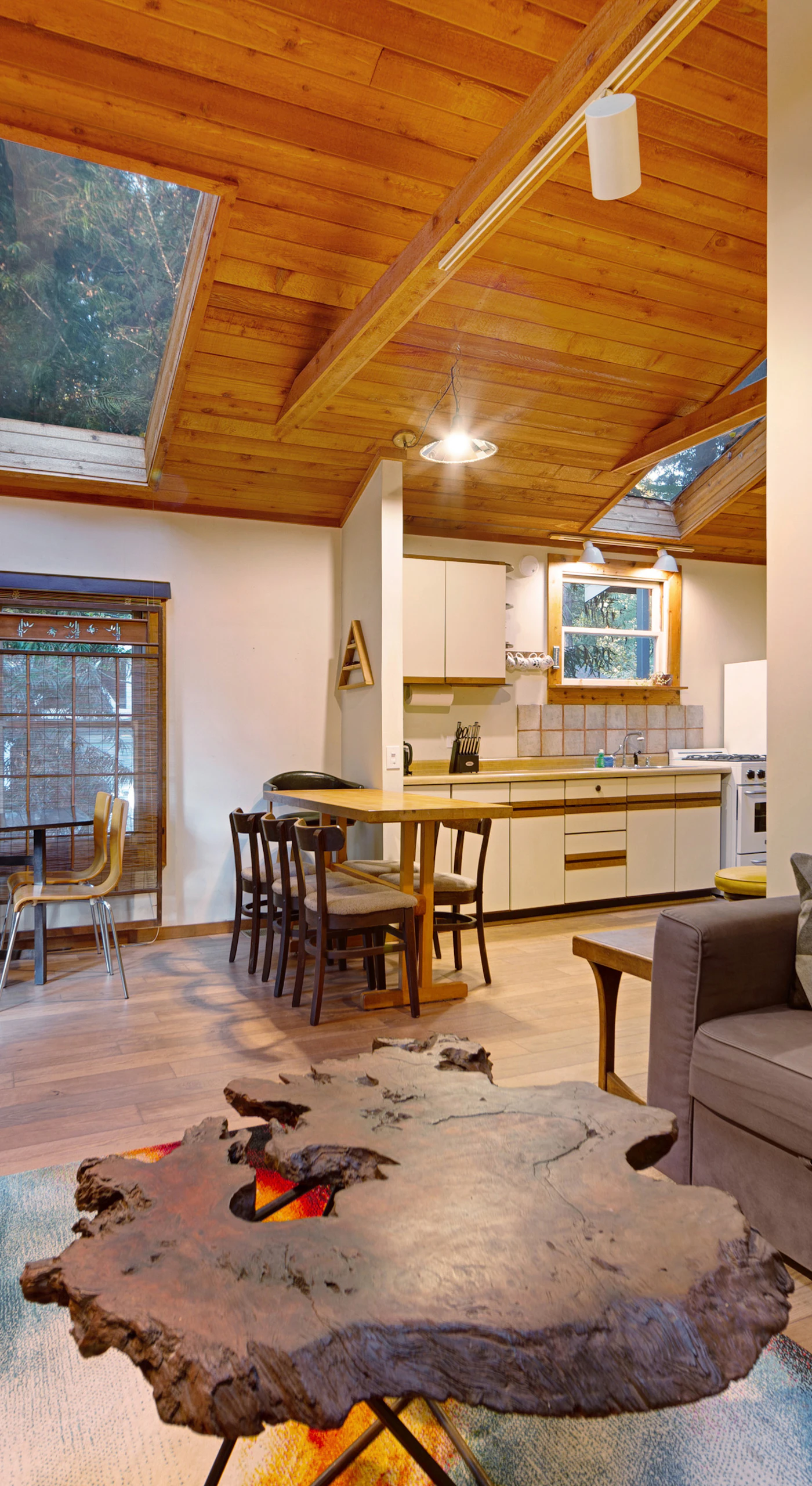 Gather in the open-plan living area where vaulted wood ceilings, eclectic art, and a live-edge coffee table set a warm wine country tone.
