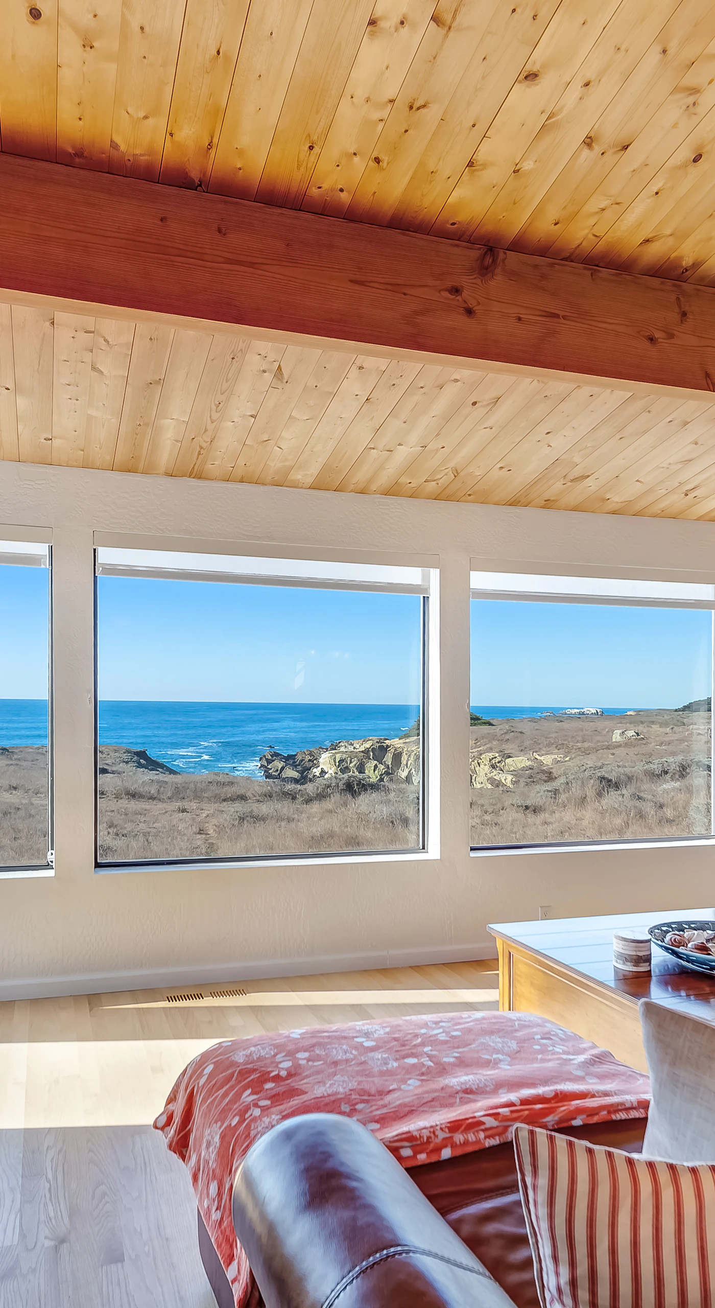 Morning light floods the living room, inviting you to relax and soak in panoramic ocean vistas from the comfort of plush seating and a non-operational decorative fireplace.