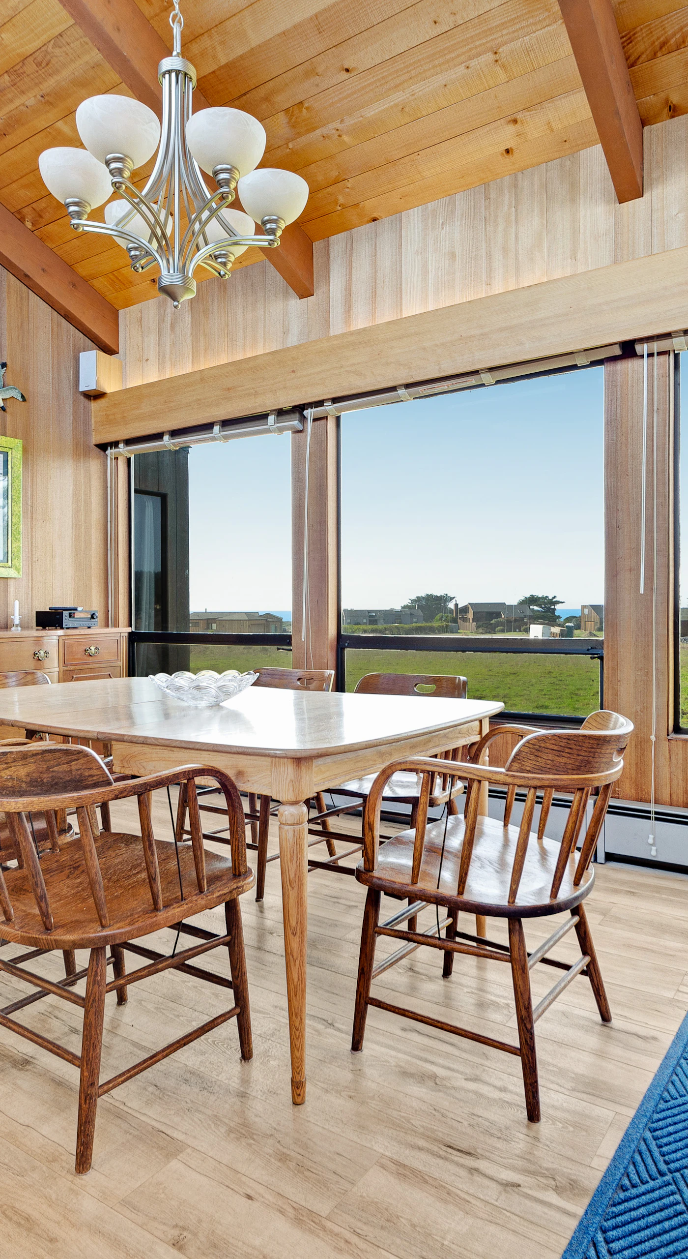 Share laughter and meals in this dining area, complete with panoramic windows that frame ocean views and the lush landscape.