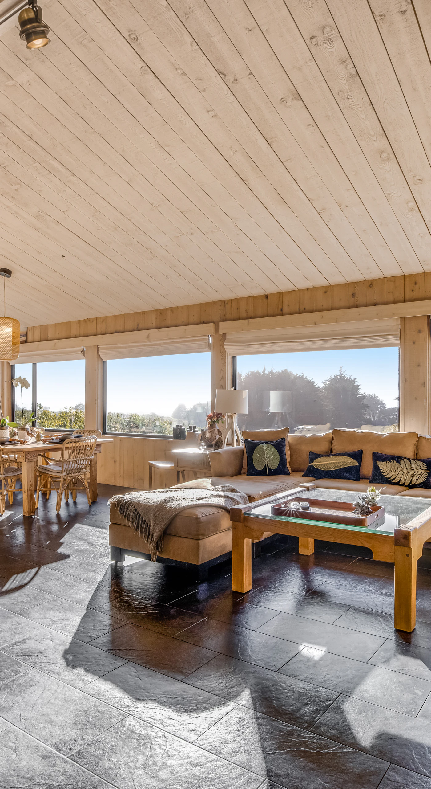 The spacious living room invites you to unwind, with panoramic windows framing the beauty of nature outside.
