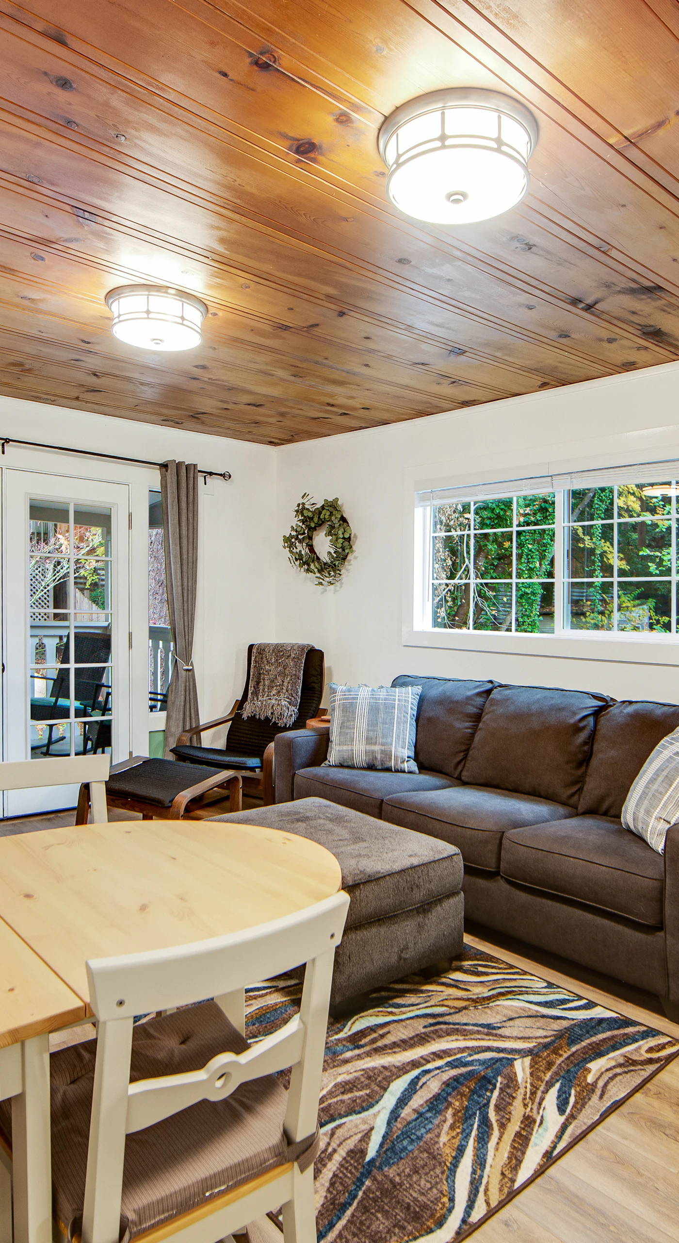 Sink into the cozy sectional beneath warm wood-paneled ceilings after a day exploring Guerneville's redwood trails. French doors flood the room with natural light.
