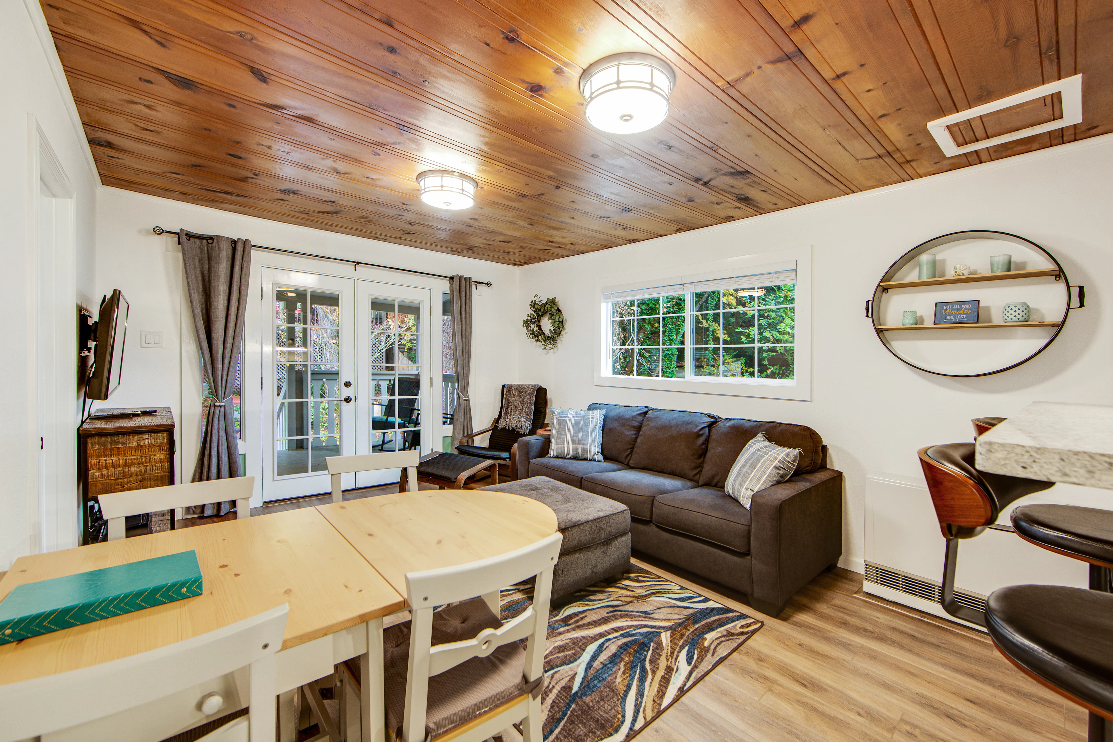 Sink into the cozy sectional beneath warm wood-paneled ceilings after a day exploring Guerneville's redwood trails. French doors flood the room with natural light.