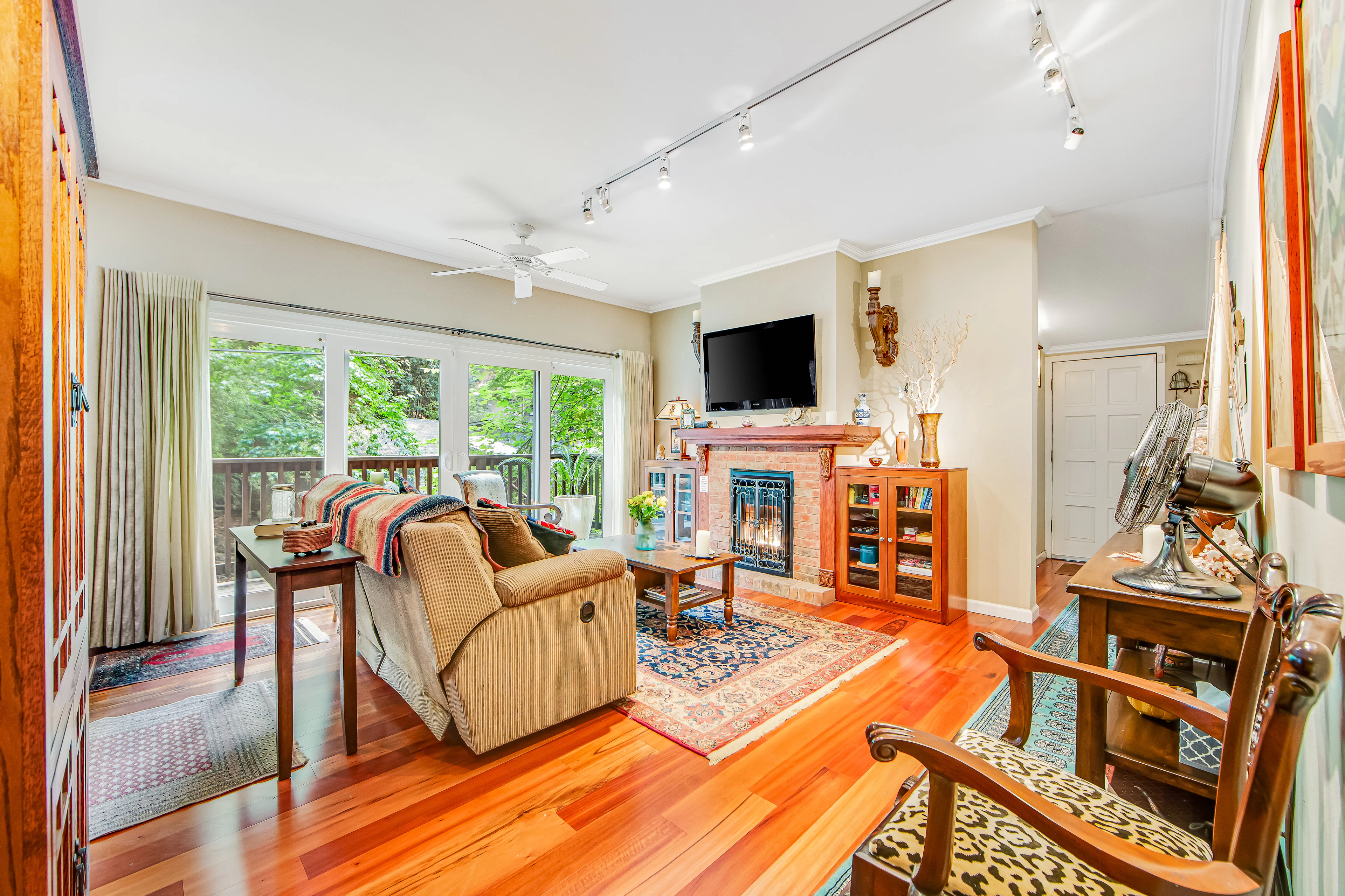 Settle into your sun-drenched living room with gleaming hardwood floors, a cozy brick fireplace, and floor-to-ceiling windows framing the redwood canopy outside your door.