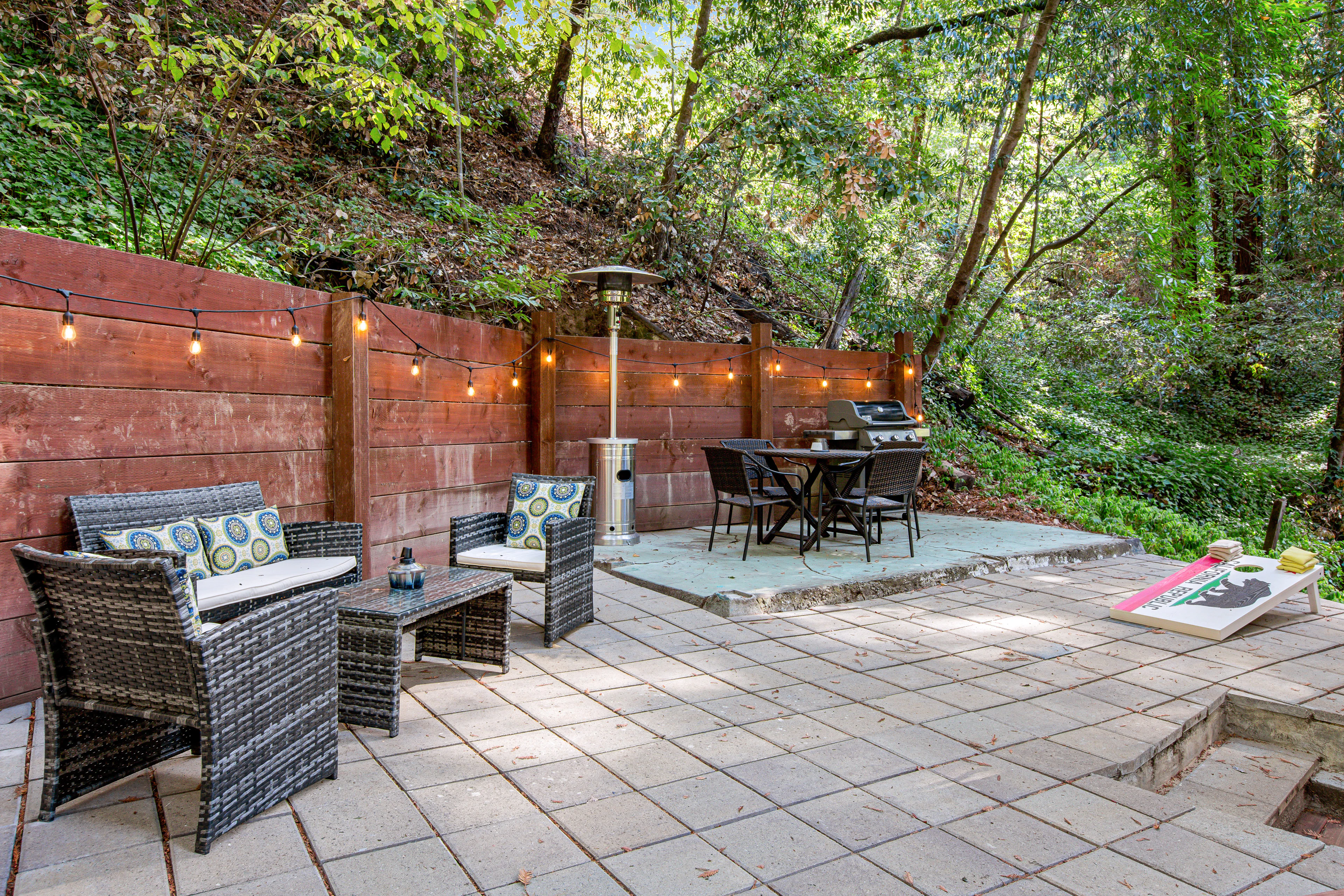 Unwind beneath twinkling string lights on your private patio — lounge seating, outdoor dining, and a cornhole board nestled among towering Guerneville redwoods.