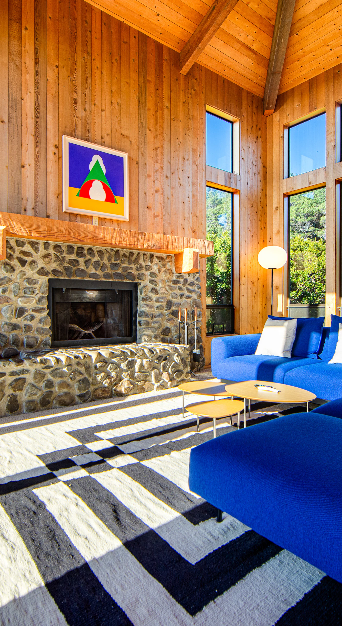 Relax on the plush blue sofa while enjoying views of the lush greenery outside, creating a perfect backdrop for your coastal getaway.