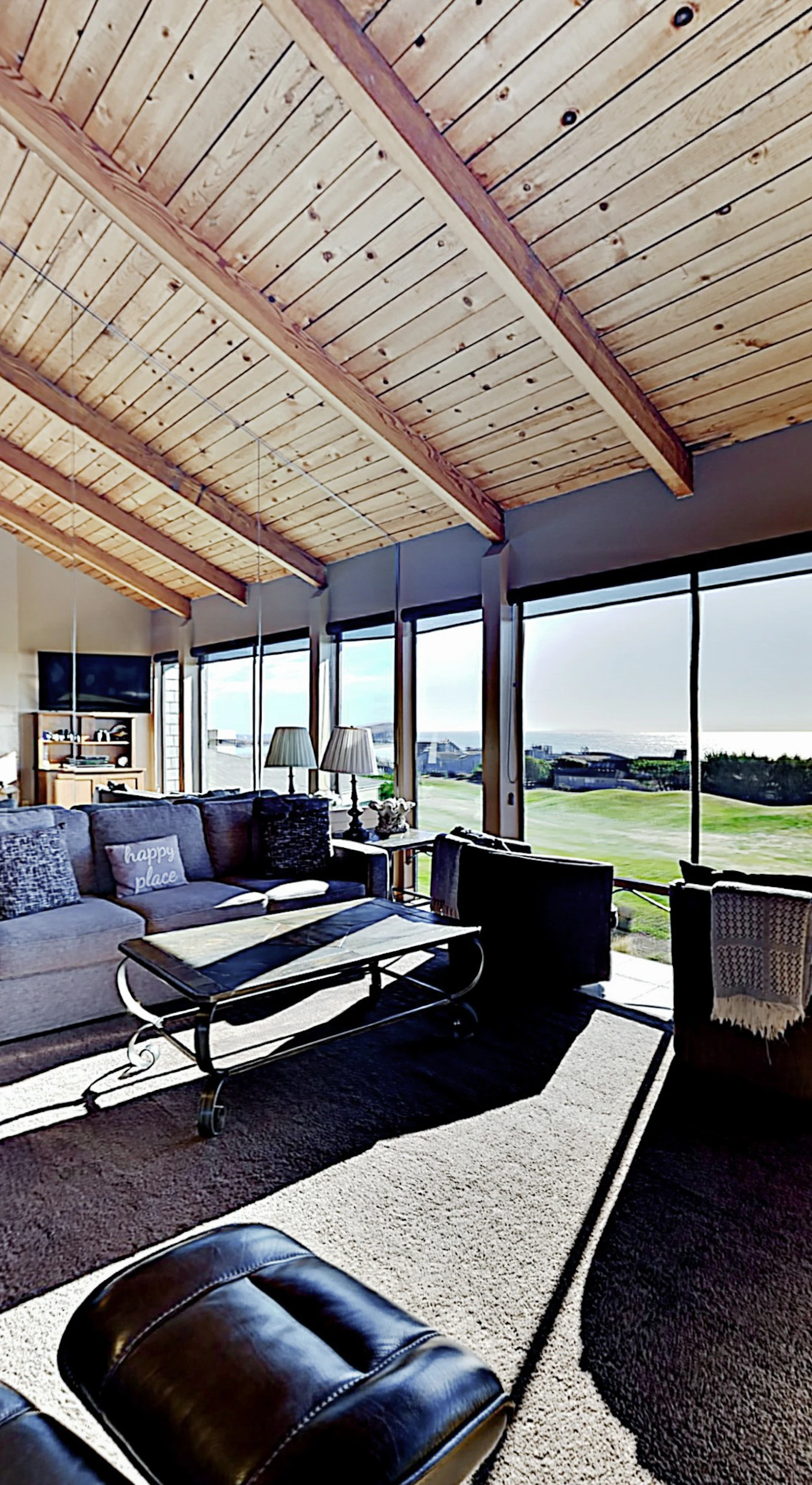 Spread out across multiple seating areas in this sun-filled great room — your floor-to-ceiling windows frame the golf course greens and distant Pacific blue.