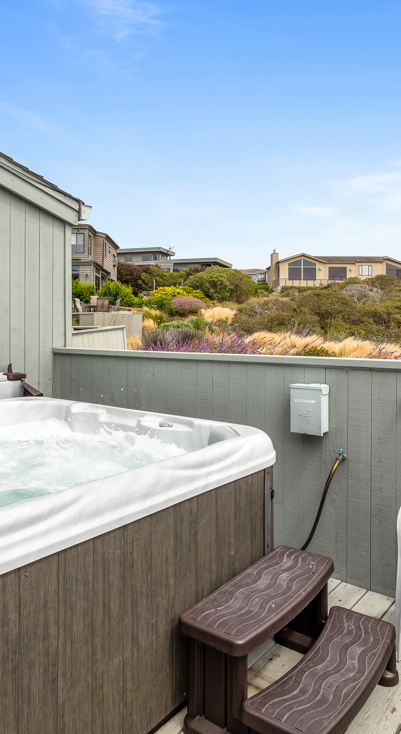 Bubbling and ready, your private hot tub sits on a sunny upper deck with views across the coastal neighborhood.