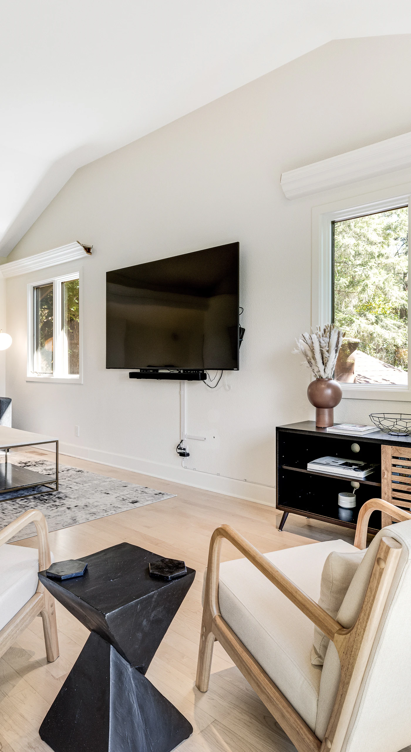 Bright and airy, your main living space welcomes you with modern furnishings, a wall-mounted TV, and sun-drenched windows framing the Sonoma County hillside.
