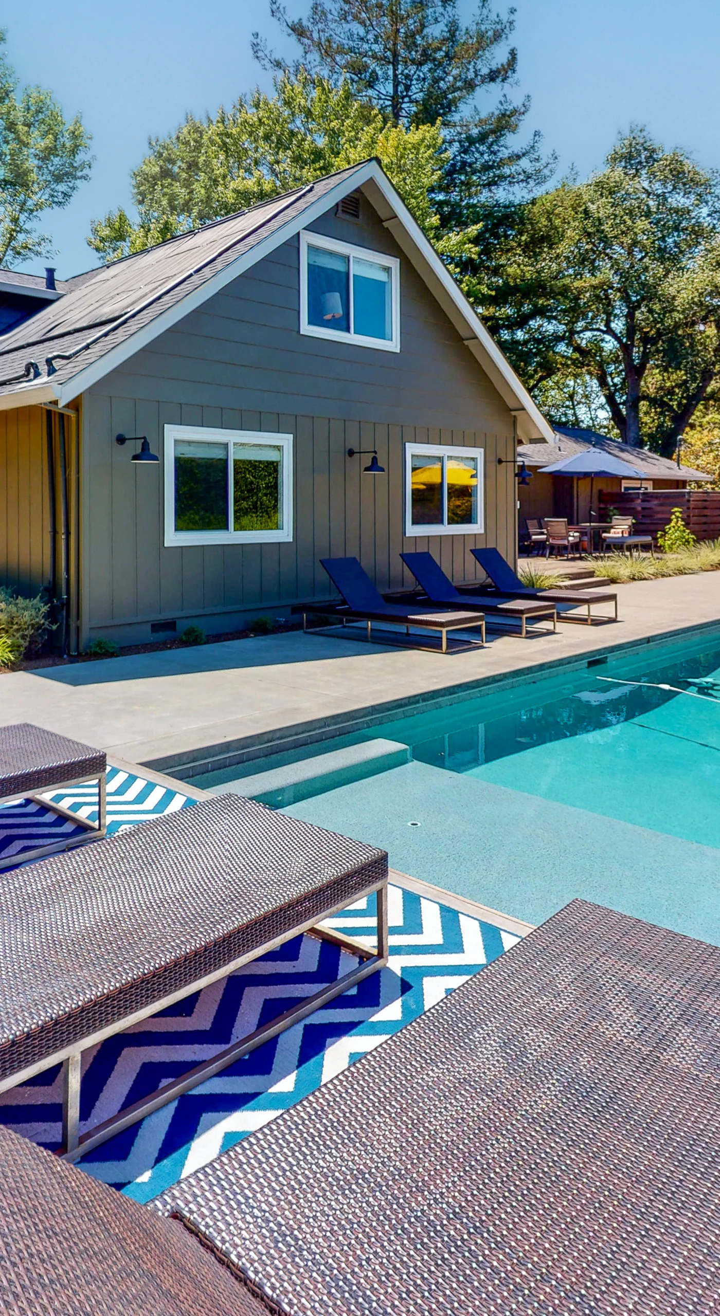 Dive into your Sonoma wine country escape — a sparkling private pool flanked by striped loungers awaits after a day exploring nearby tasting rooms.