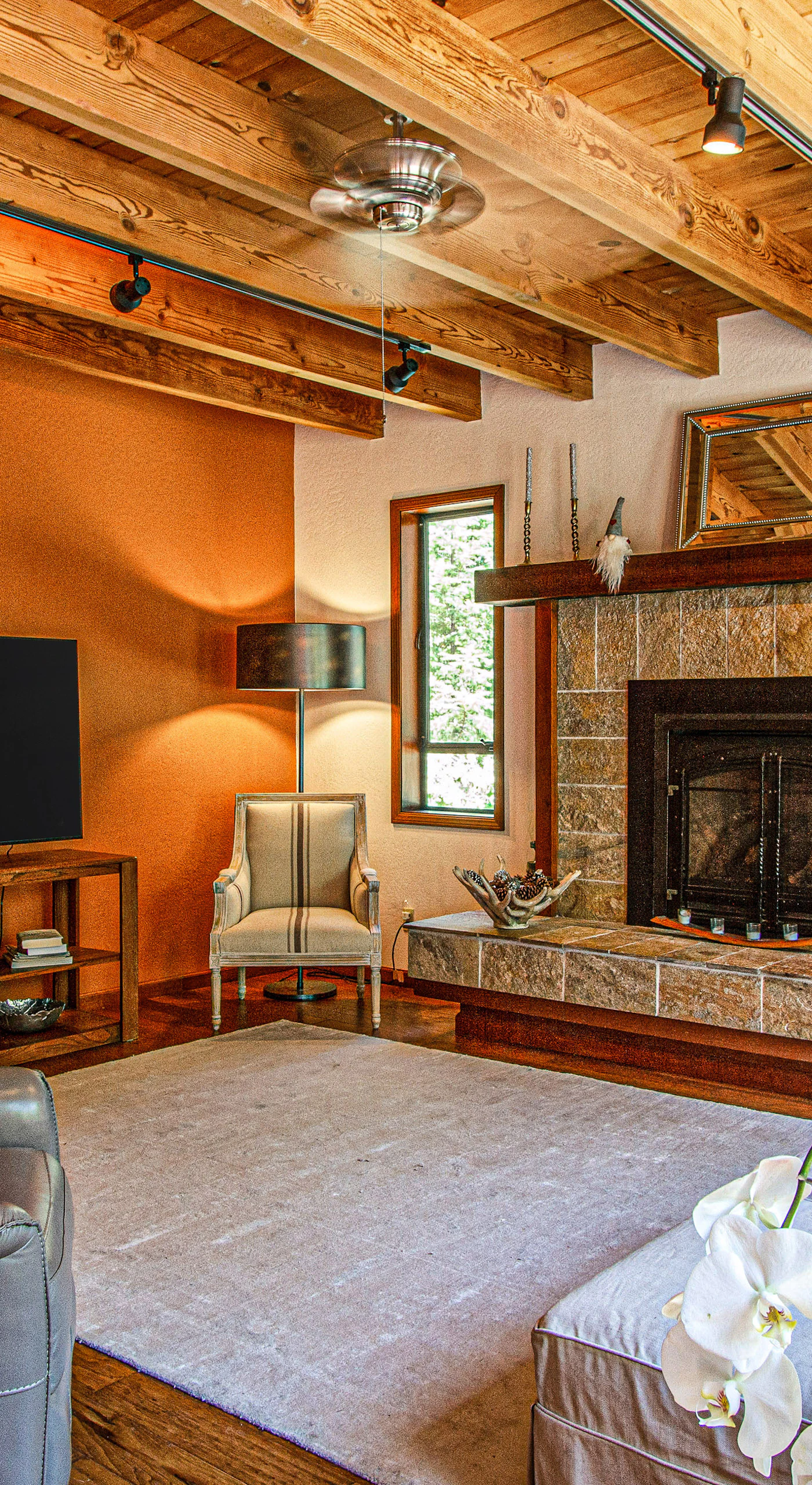 Unwind by the stone-hearth gas fireplace in a vaulted living room with exposed timber beams, a large flat-screen TV, and plush seating for your whole group.