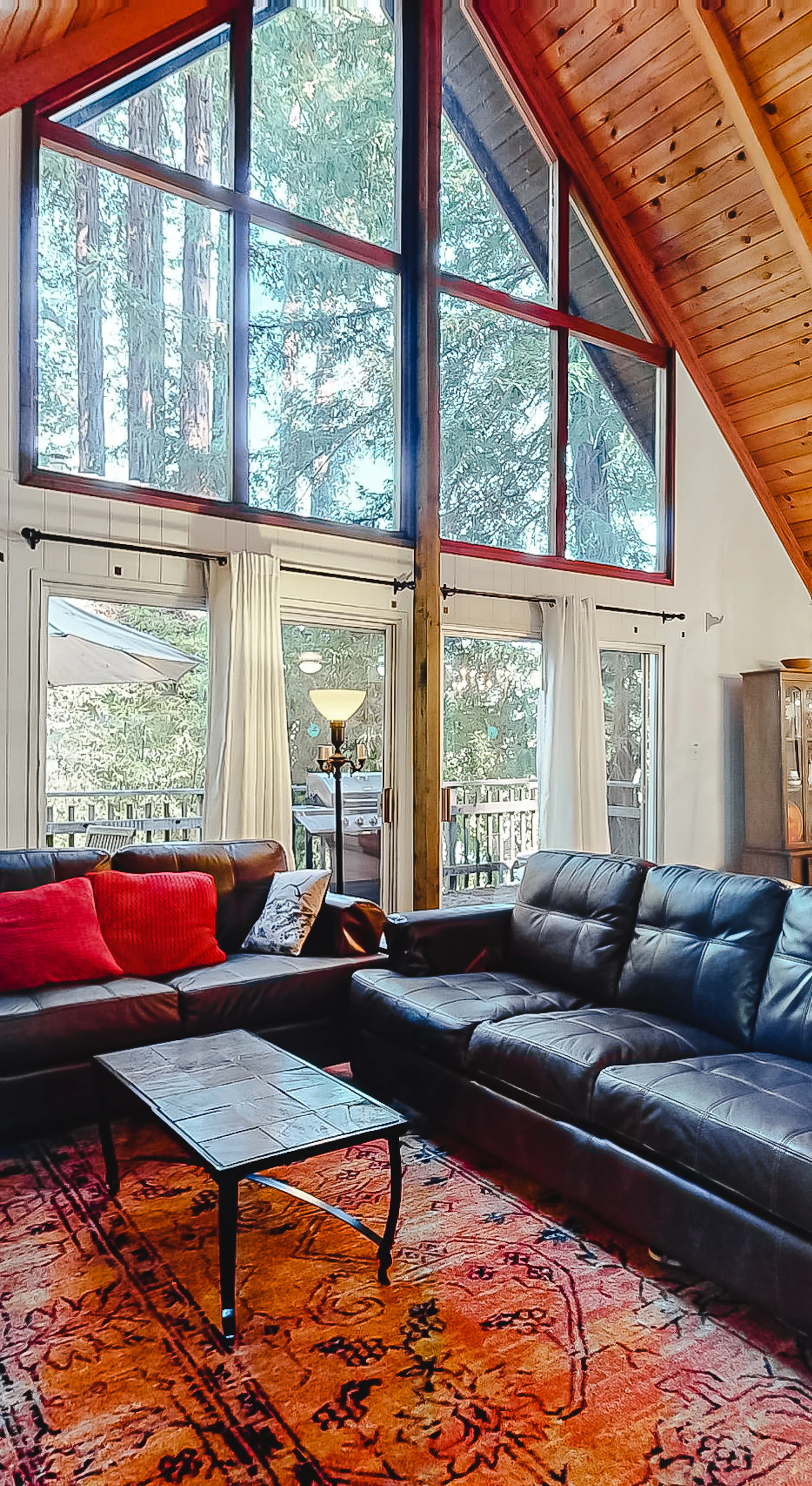 Soaring A-frame ceilings clad in warm wood frame your living room — sink into leather sofas and gaze through floor-to-ceiling redwood canopy windows.