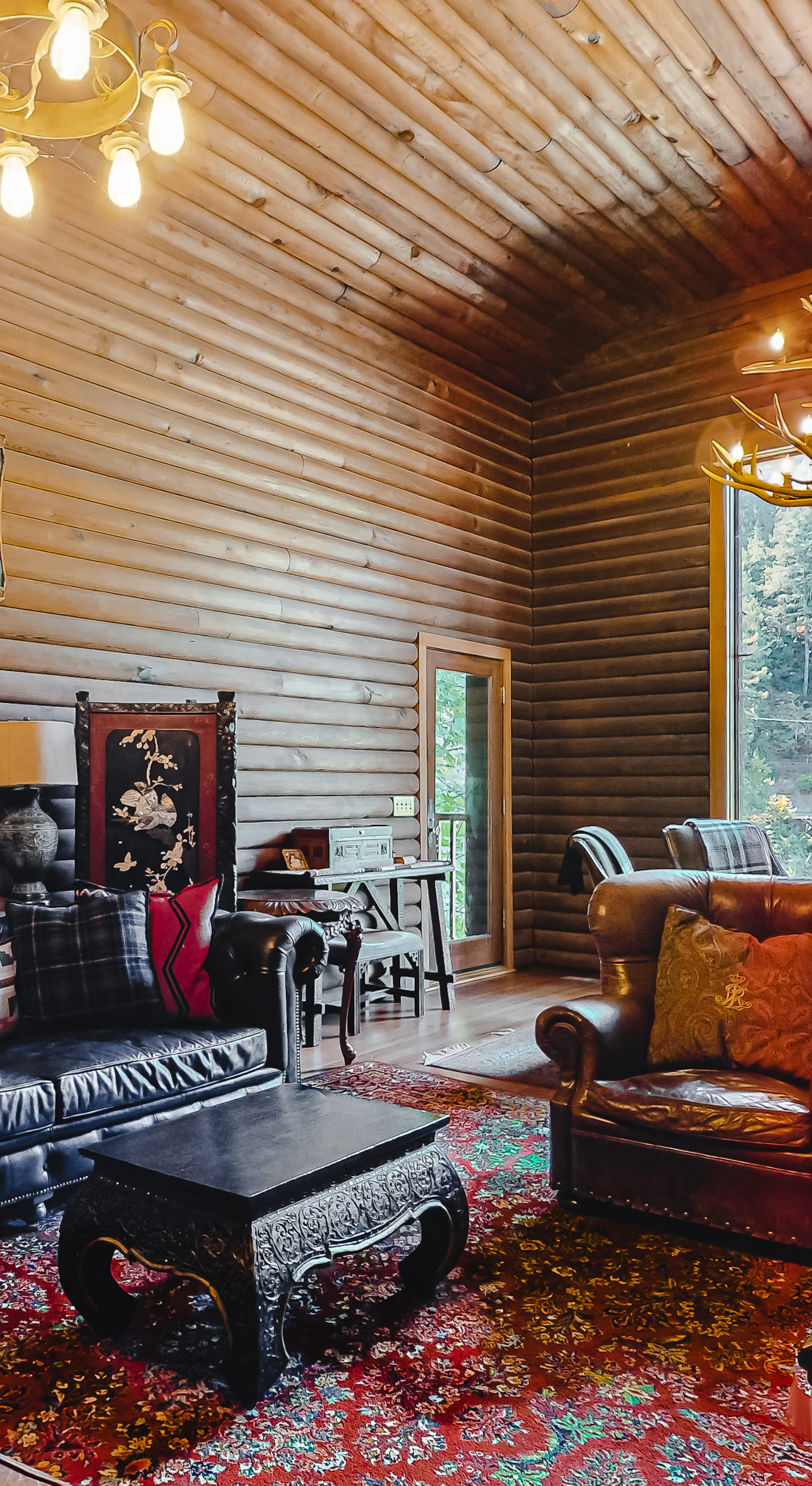 Sink into leather sofas under a showpiece antler chandelier — vaulted log ceilings and a panoramic window frame your Russian River retreat perfectly.
