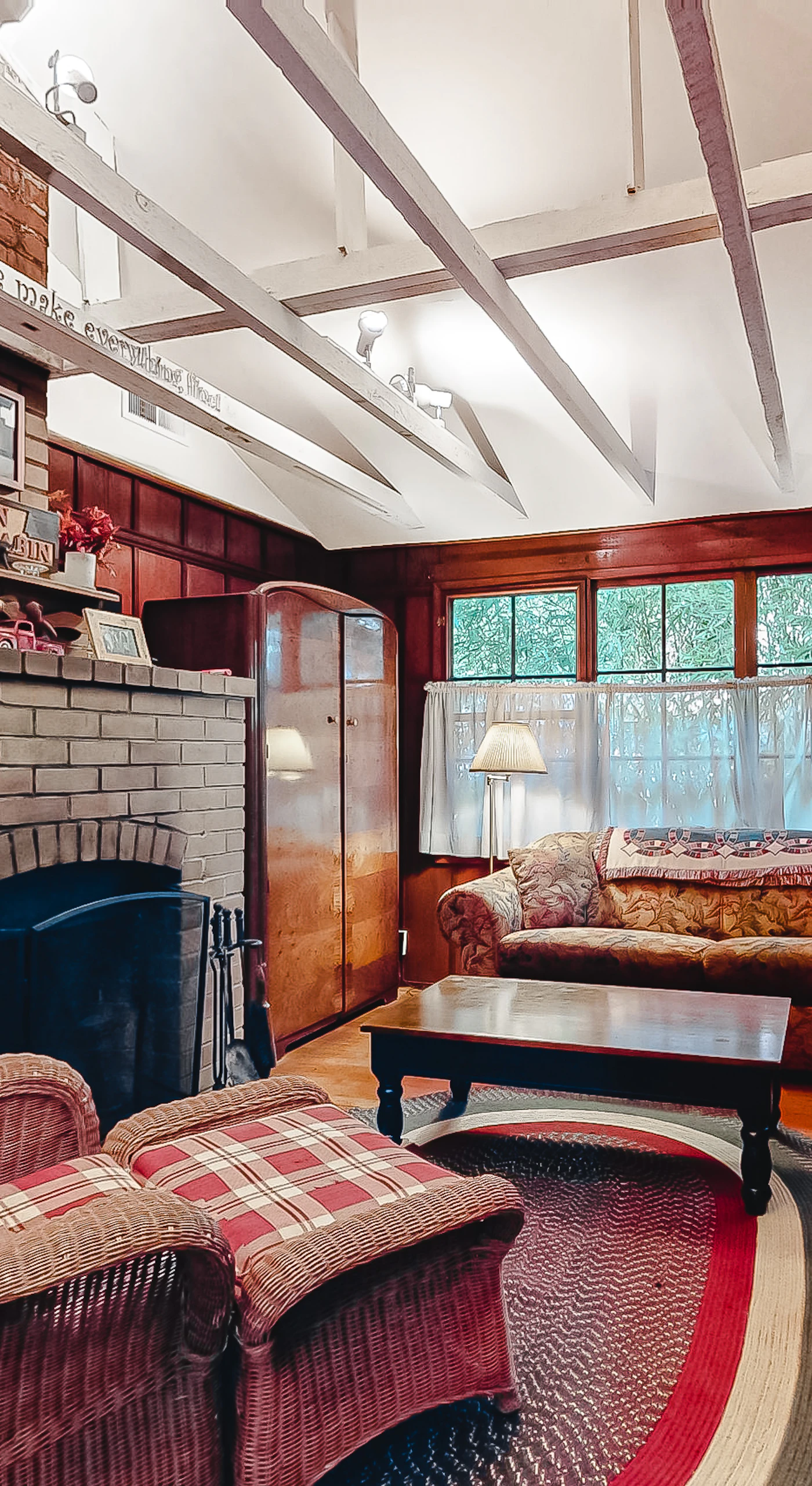 Sink into cozy wicker chairs beside your wood-burning brick fireplace — rich wood paneling and vaulted beams set the tone for a true redwood retreat evening.