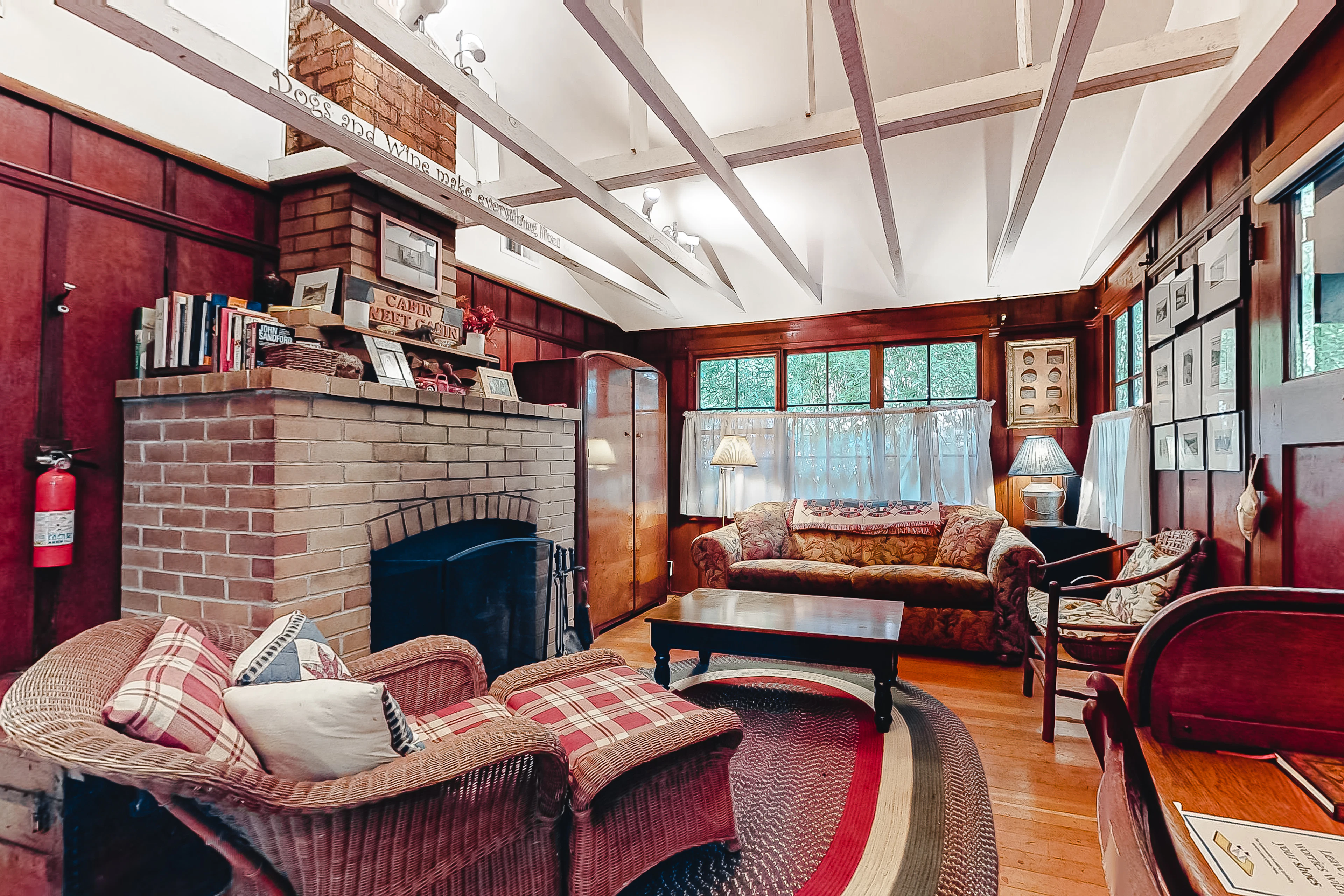 Sink into cozy wicker chairs beside your wood-burning brick fireplace — rich wood paneling and vaulted beams set the tone for a true redwood retreat evening.