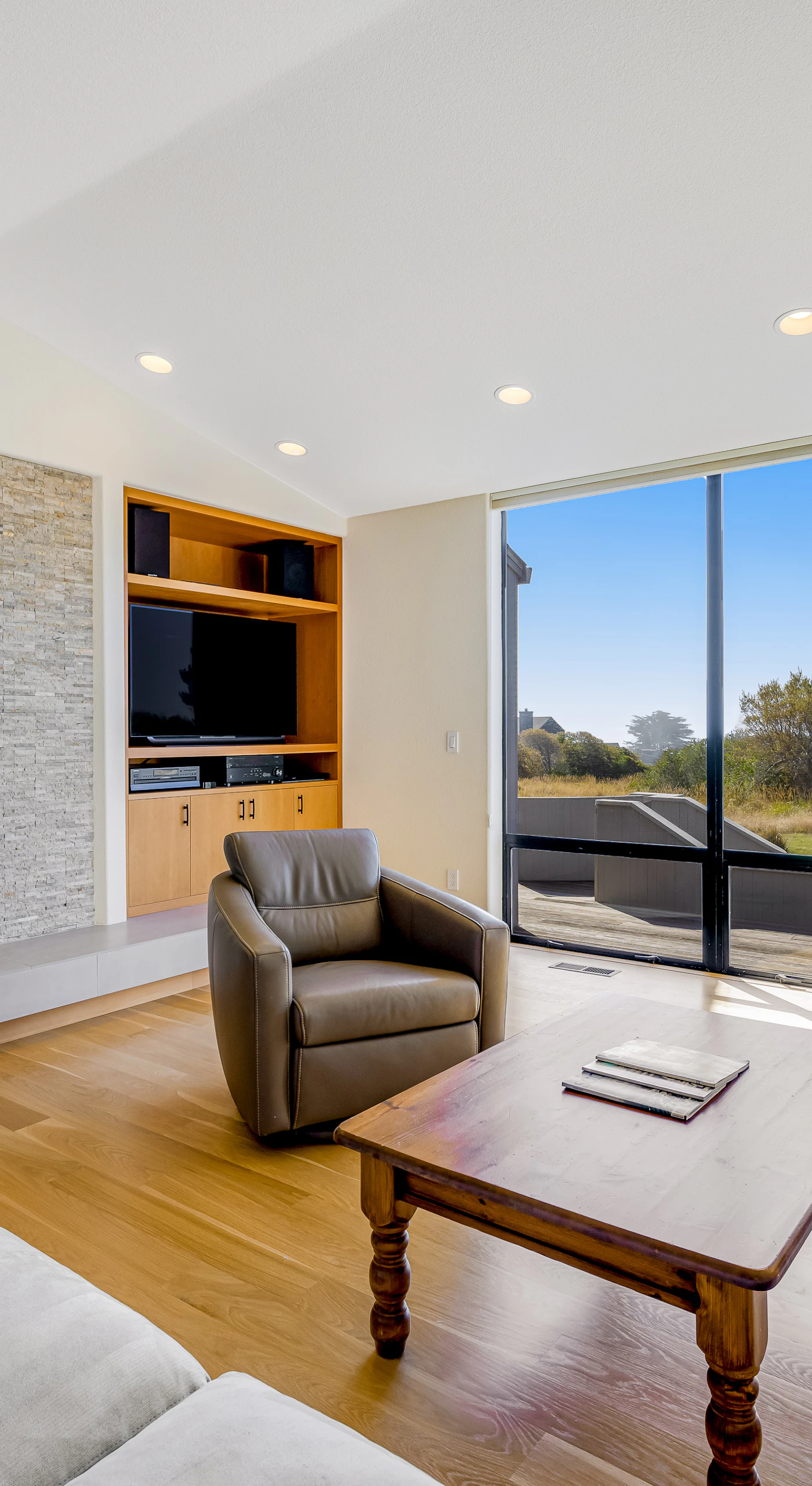The living room invites you to unwind by the fireplace, where panoramic windows frame stunning coastal vistas.