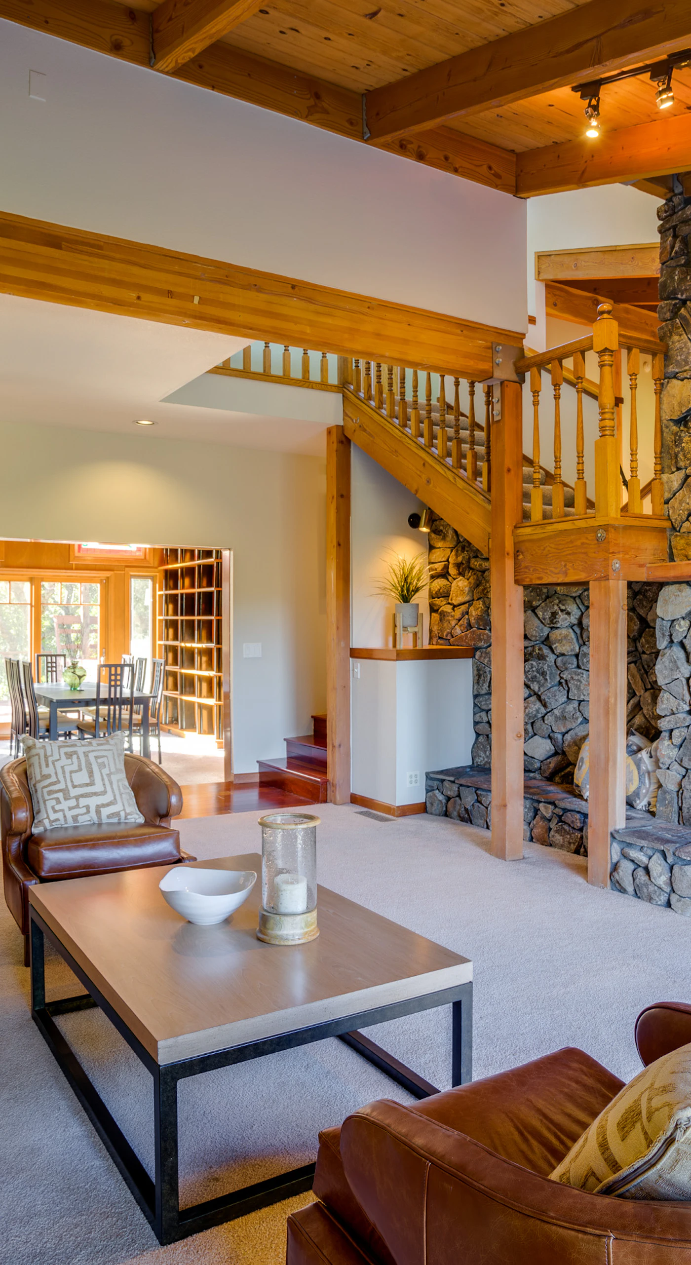 Gather your group across plush seating beneath soaring cathedral ceilings — the floor-to-ceiling stone fireplace anchors this lodge-like great room.