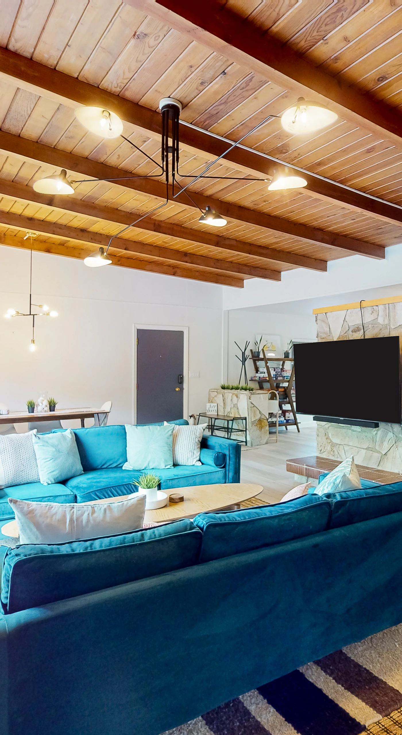 Cozy up for movie night with your group — a wall-mounted TV, dramatic stone accent wall, and track lighting make your living room the perfect redwood retreat gathering spot.