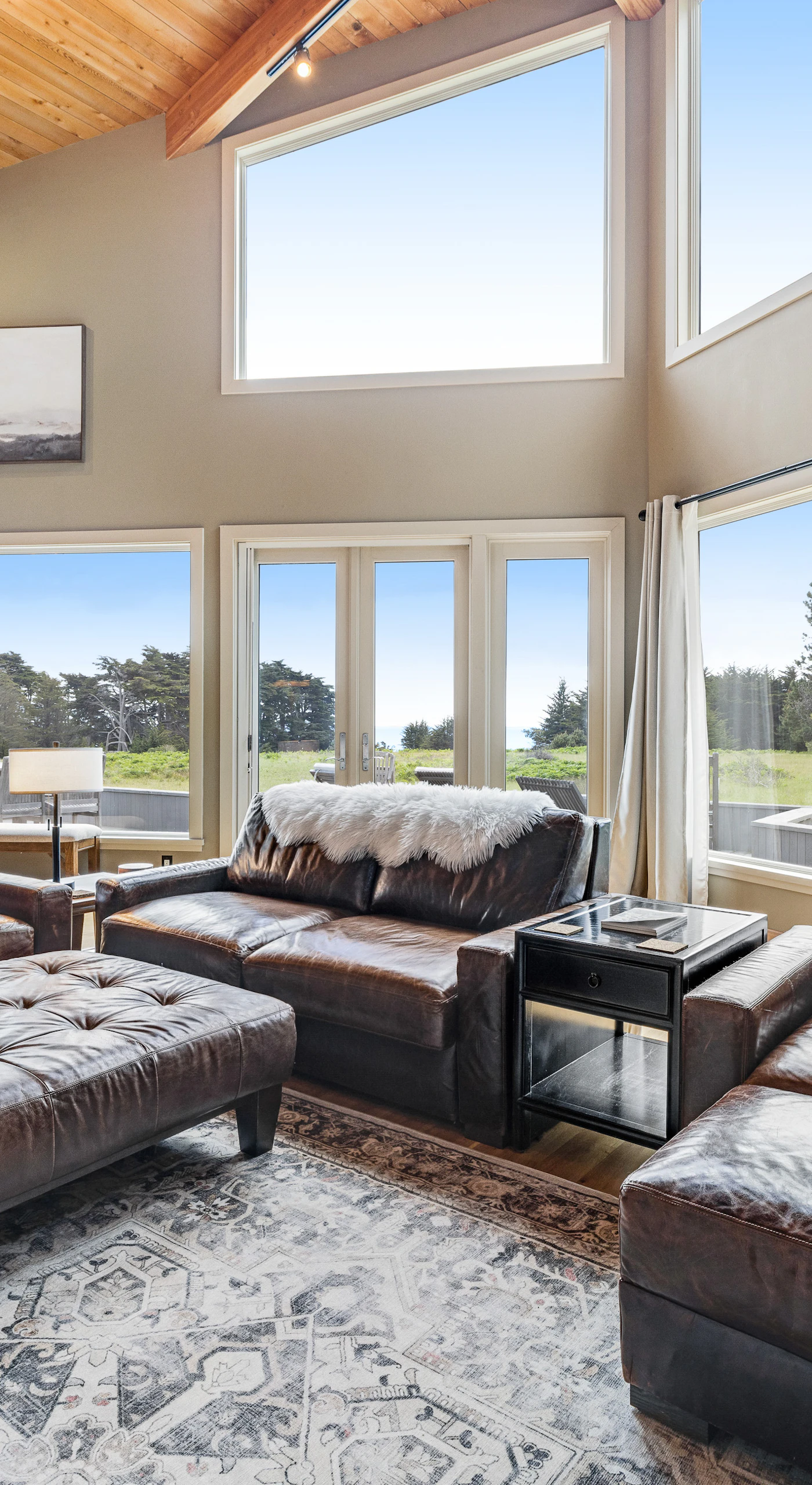 Gather with loved ones in this cozy living room, where floor-to-ceiling windows frame breathtaking coastal views.