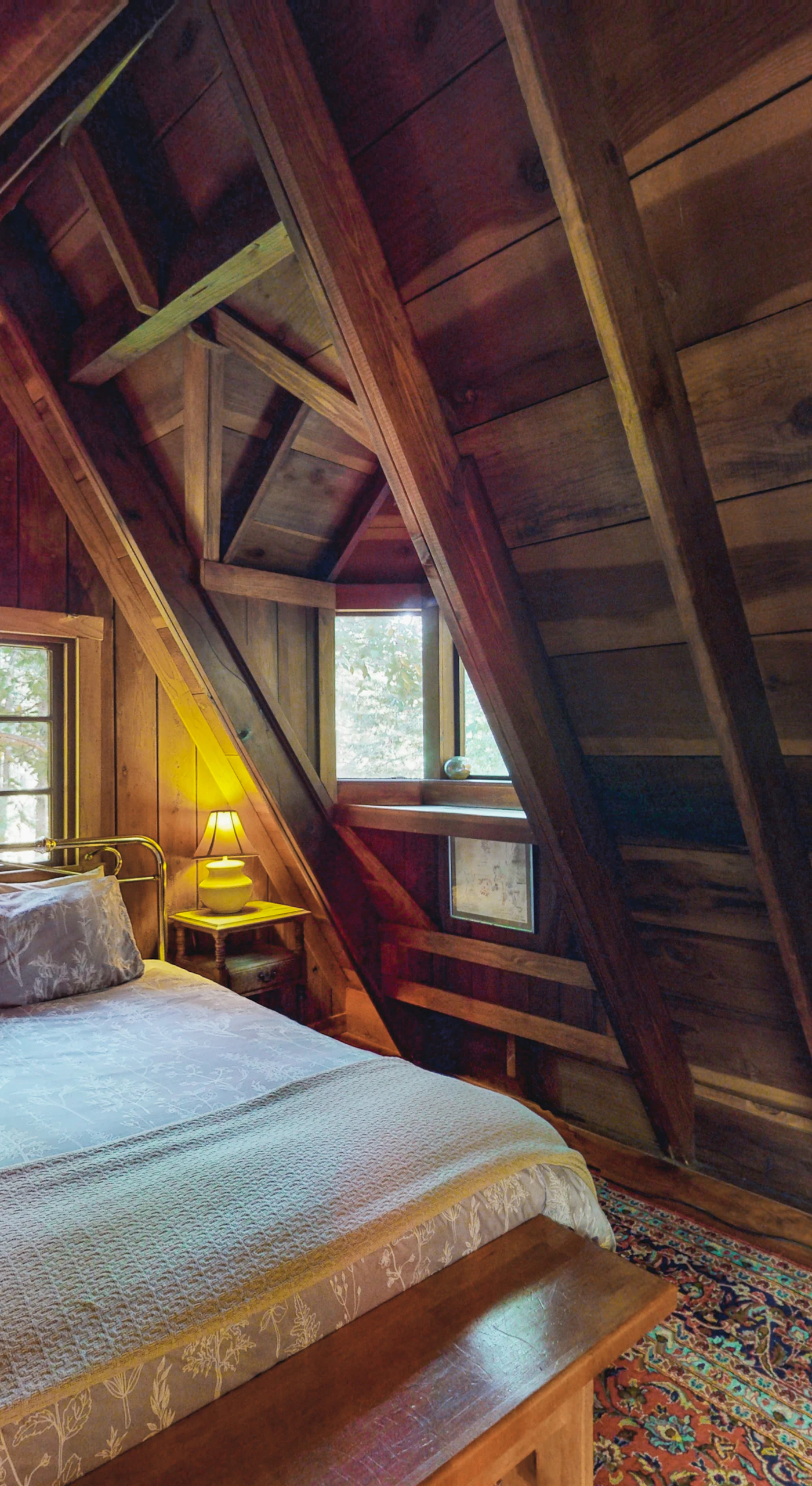 Drift off in your enchanting loft bedroom — a plush queen bed, peaked redwood A-frame ceiling, and treetop views through the dormer create your Cazadero dreamscape.