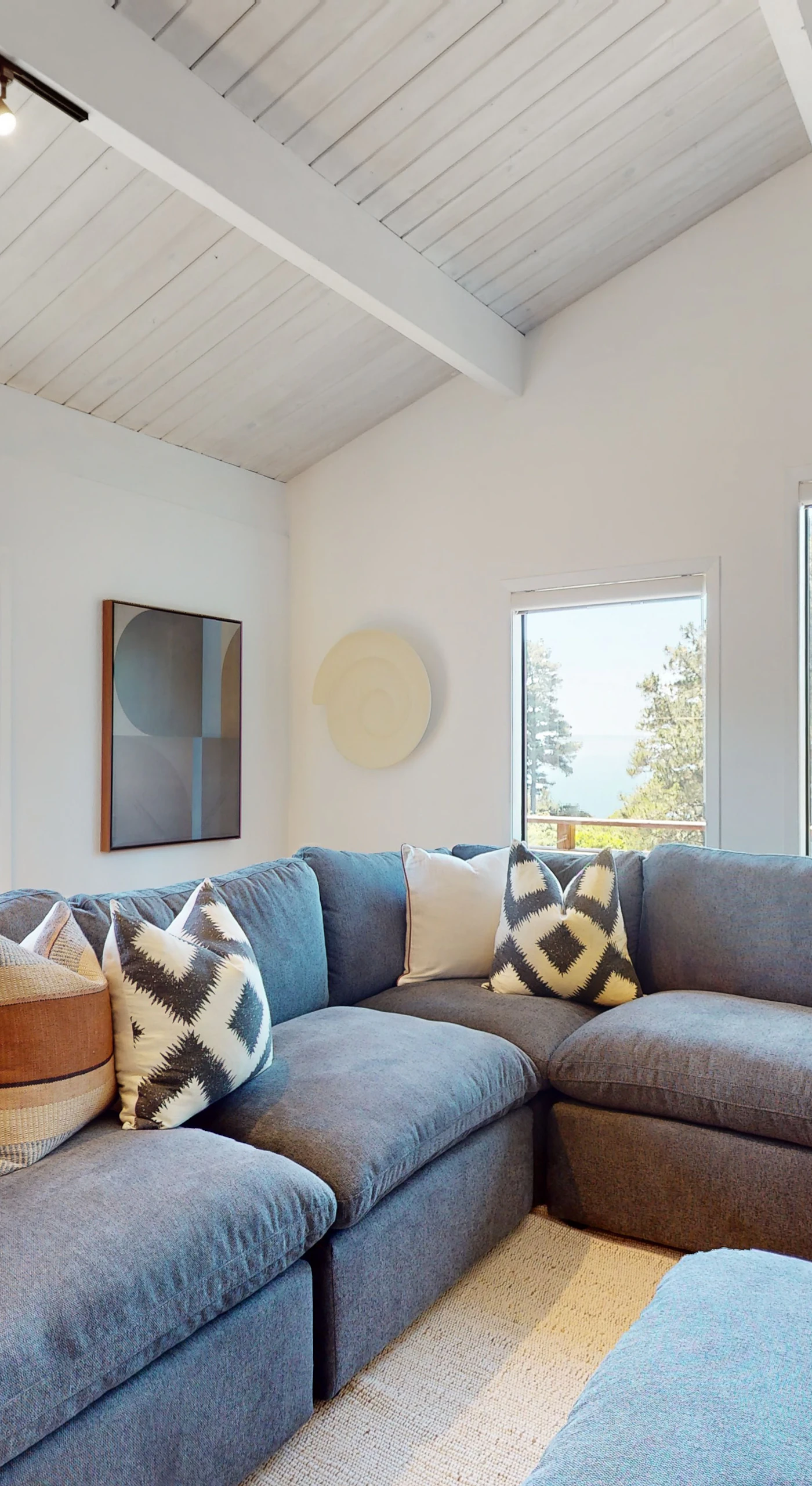 Curl up in the cozy corner of the living room, where plush seating and views of the trees create an inviting space for relaxation.