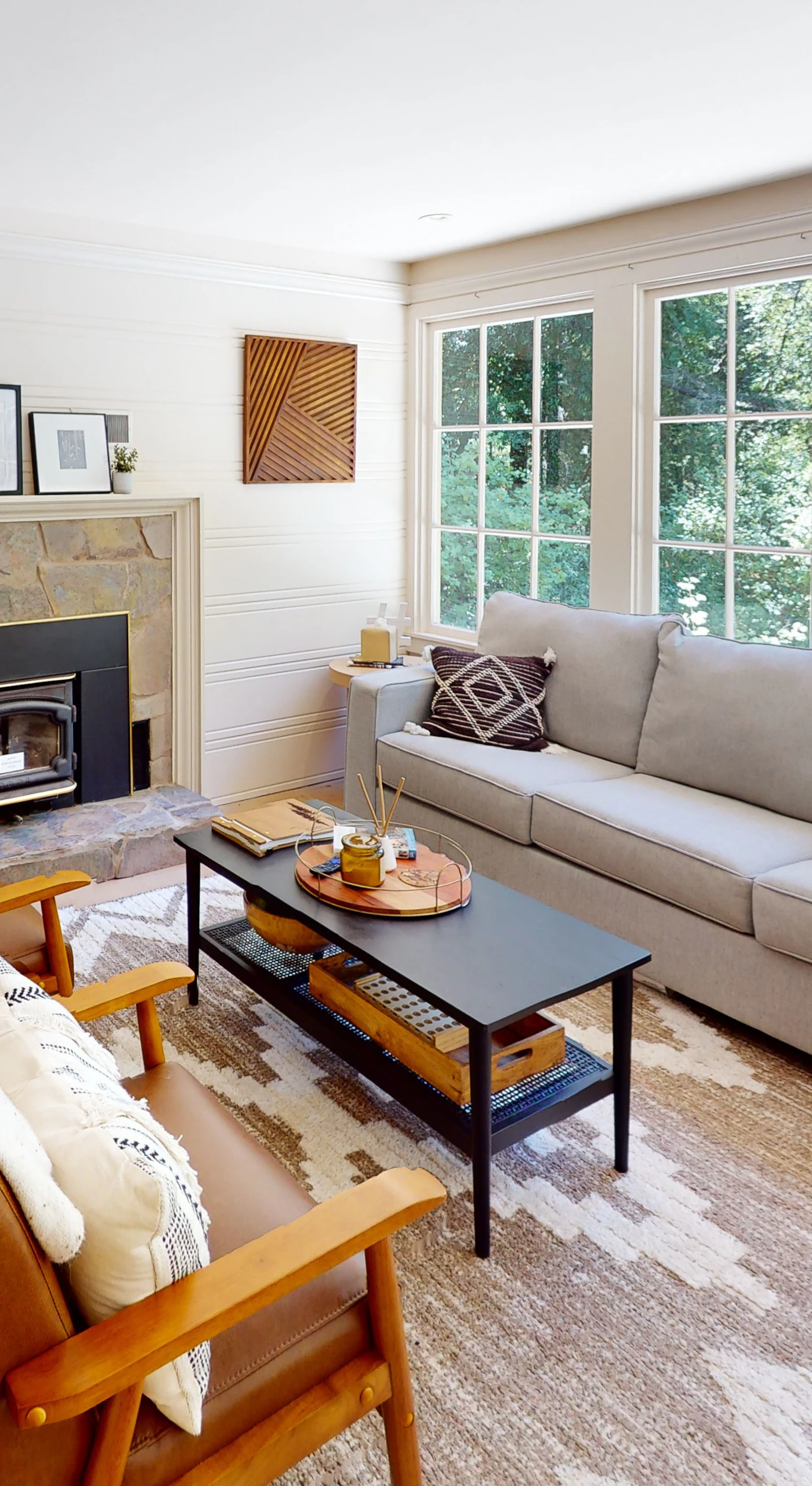Sink into your sun-drenched living room where a stone fireplace, plush seating, and walls of windows frame the surrounding redwood canopy — your Guerneville escape starts here.
