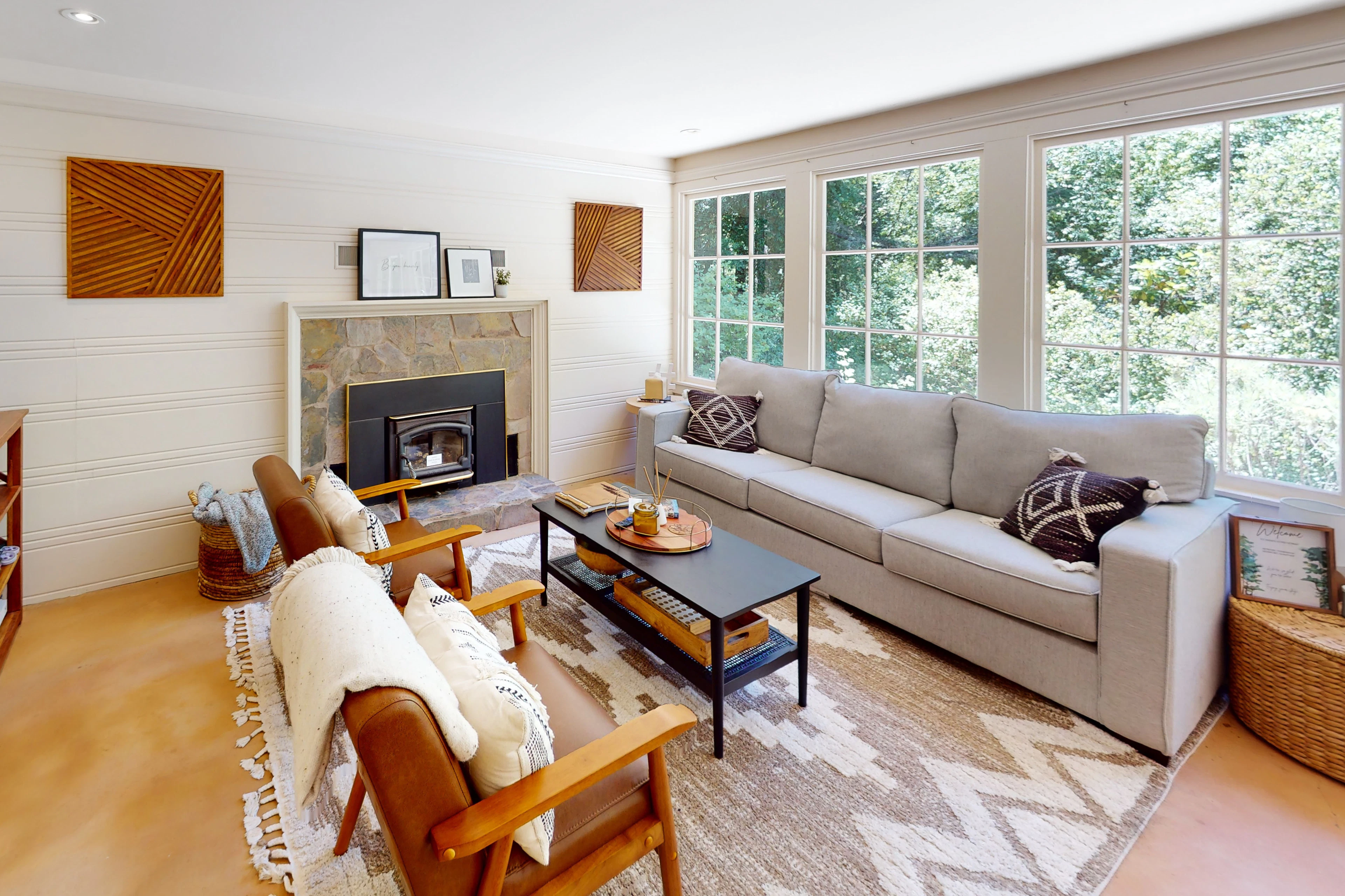 Sink into your sun-drenched living room where a stone fireplace, plush seating, and walls of windows frame the surrounding redwood canopy — your Guerneville escape starts here.