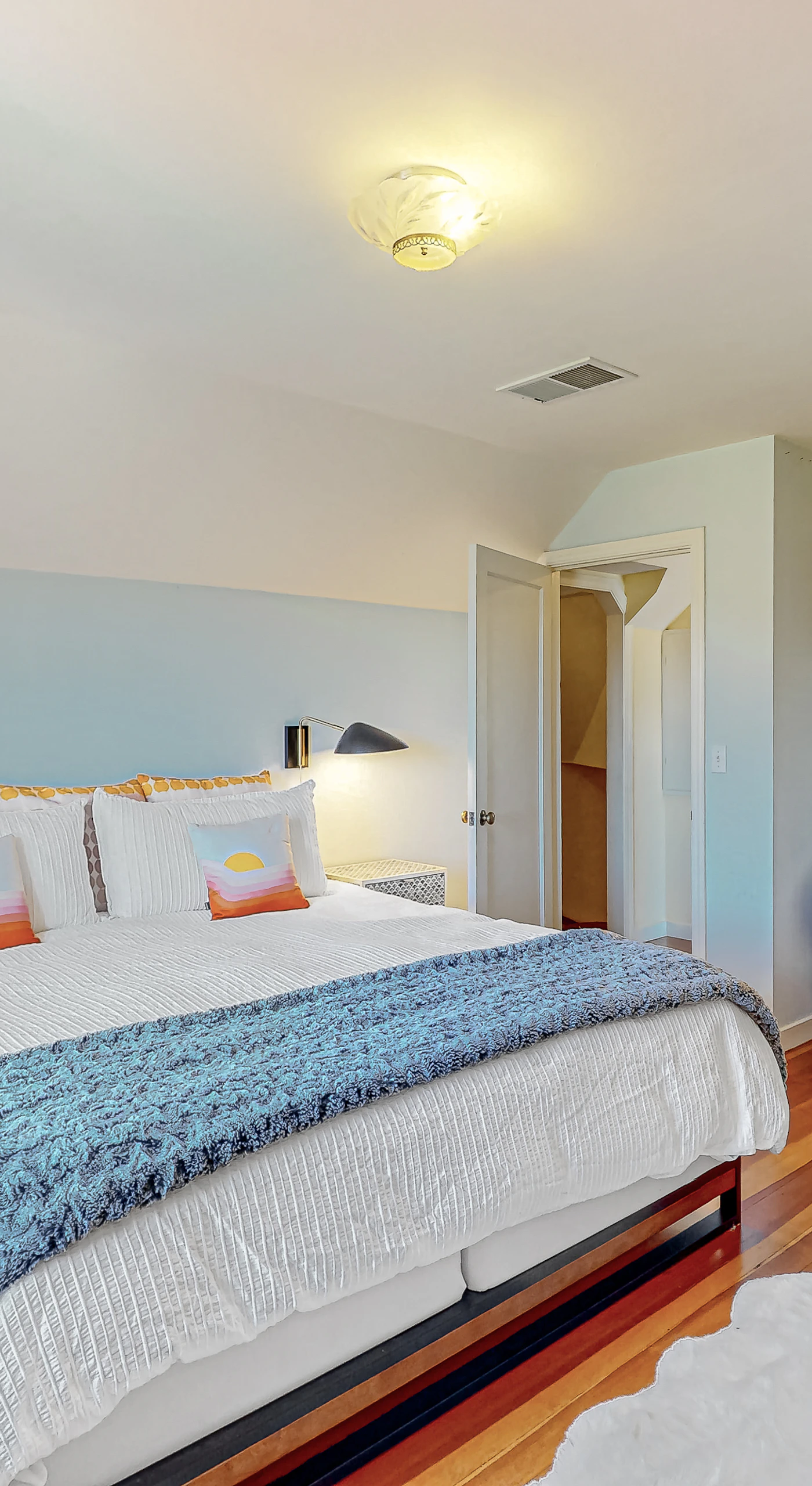Drift off in crisp white linens with a cozy blue throw after a full day of Healdsburg adventures — bedside lamps and built-in shelves keep everything within reach.