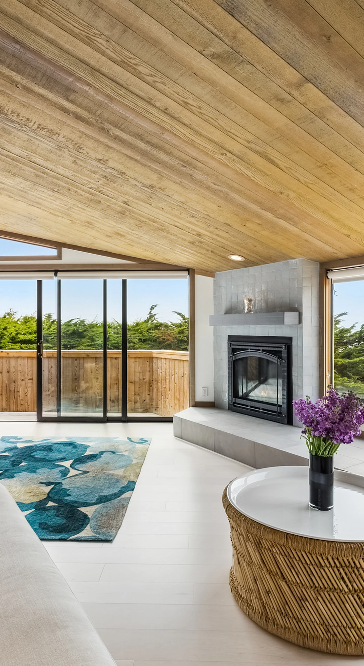 Wraparound windows frame ocean peeks and cypress treetops from every corner of your light-filled coastal living room