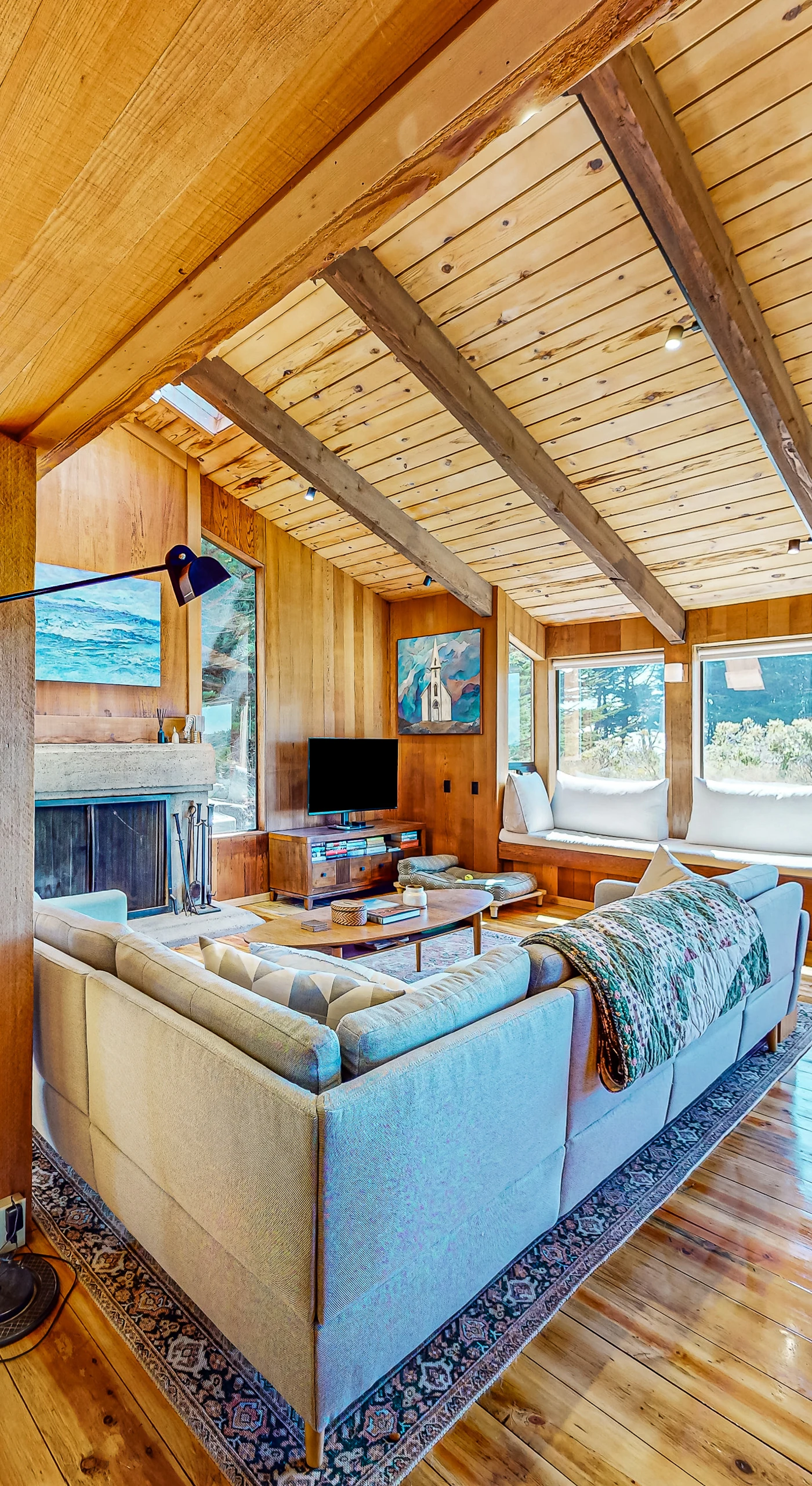 Gather around the wood-burning fireplace in this sunlit living area, perfect for cozy evenings with friends and family.