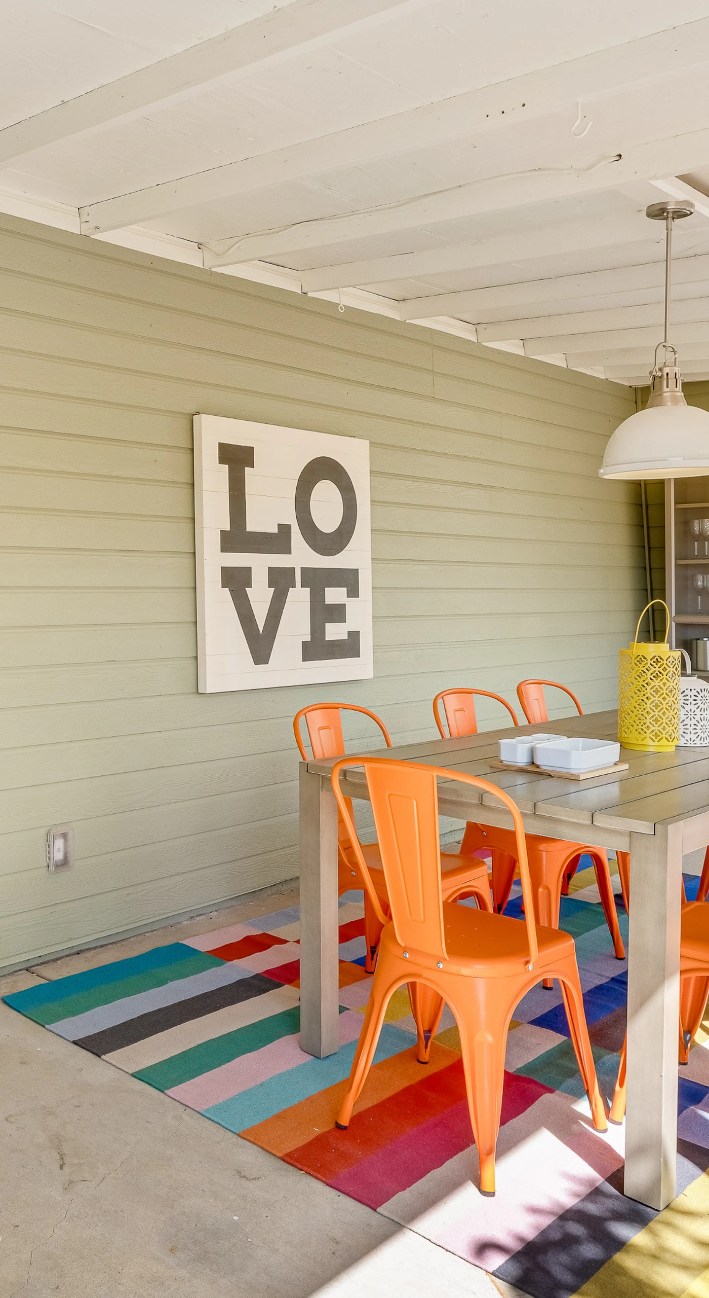 Bright orange chairs and a bold 'LOVE' sign set the tone on your covered patio — grab breakfast at the farmhouse table before your next Healdsburg tasting.