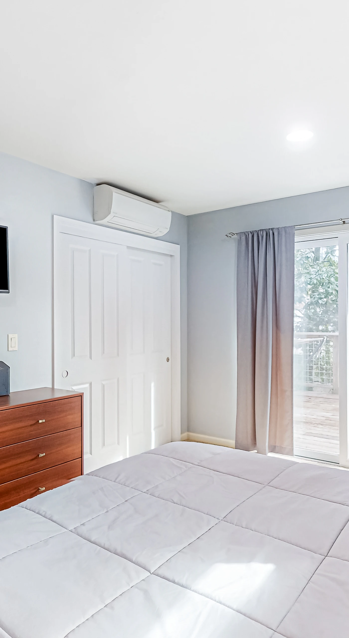 Your primary suite keeps you comfortable year-round with AC and a wall-mounted TV — step through the glass doors for morning coffee on the private deck.