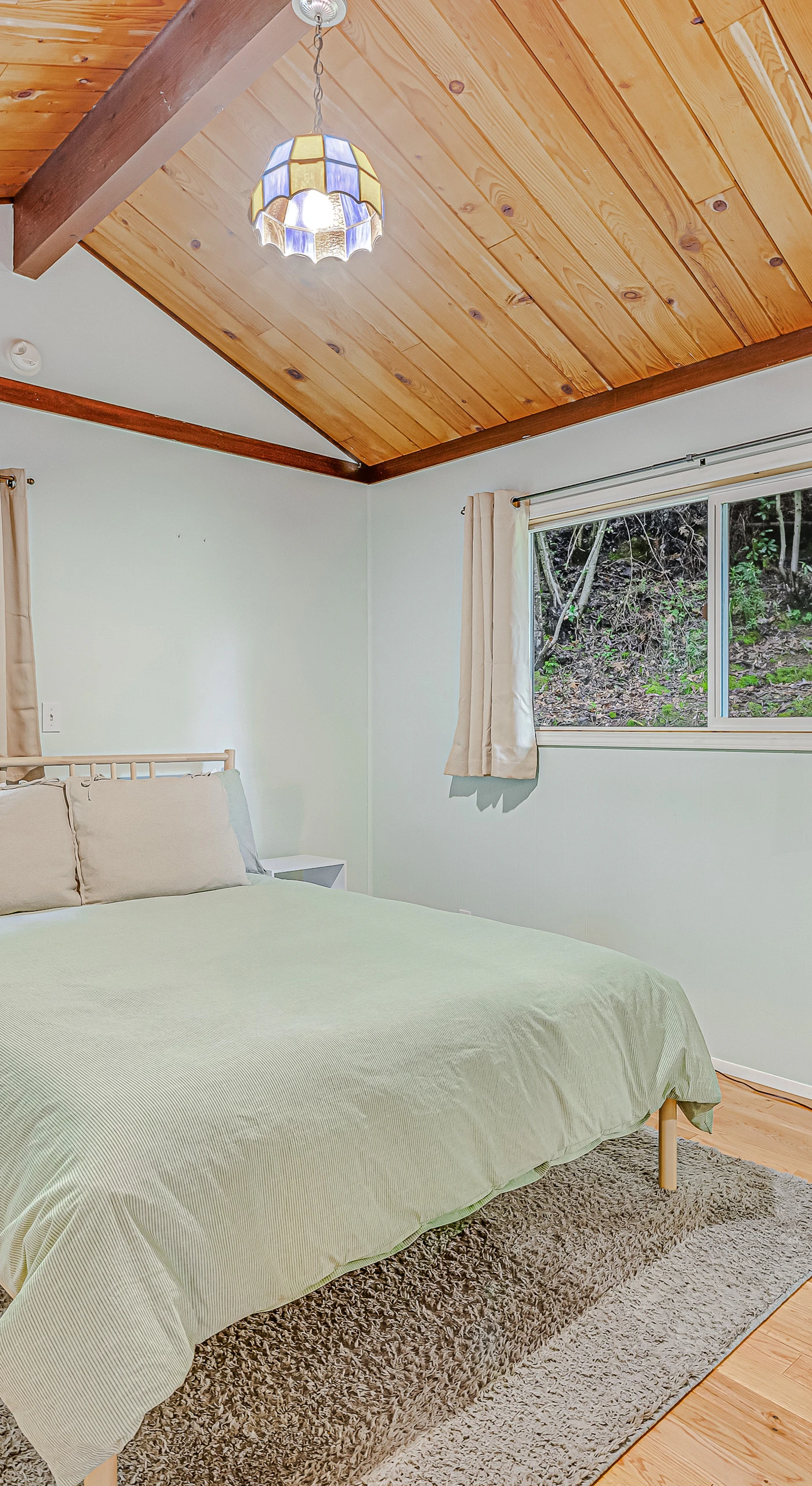 Drift off in your serene primary bedroom — a queen bed, vaulted wood ceiling, and garden-framed windows create the perfect wine country wind-down.