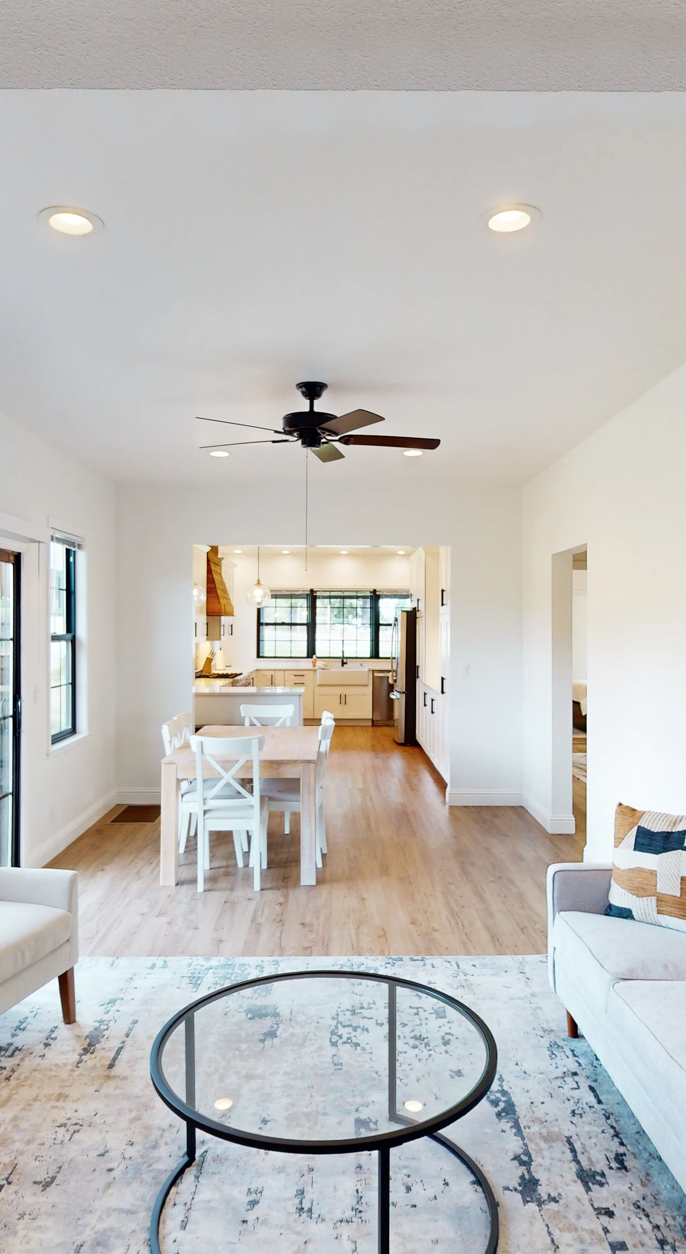 Unwind in your sun-drenched open-concept living space — plush seating, modern art, and hardwood floors flow seamlessly into the dining and chef's kitchen beyond.