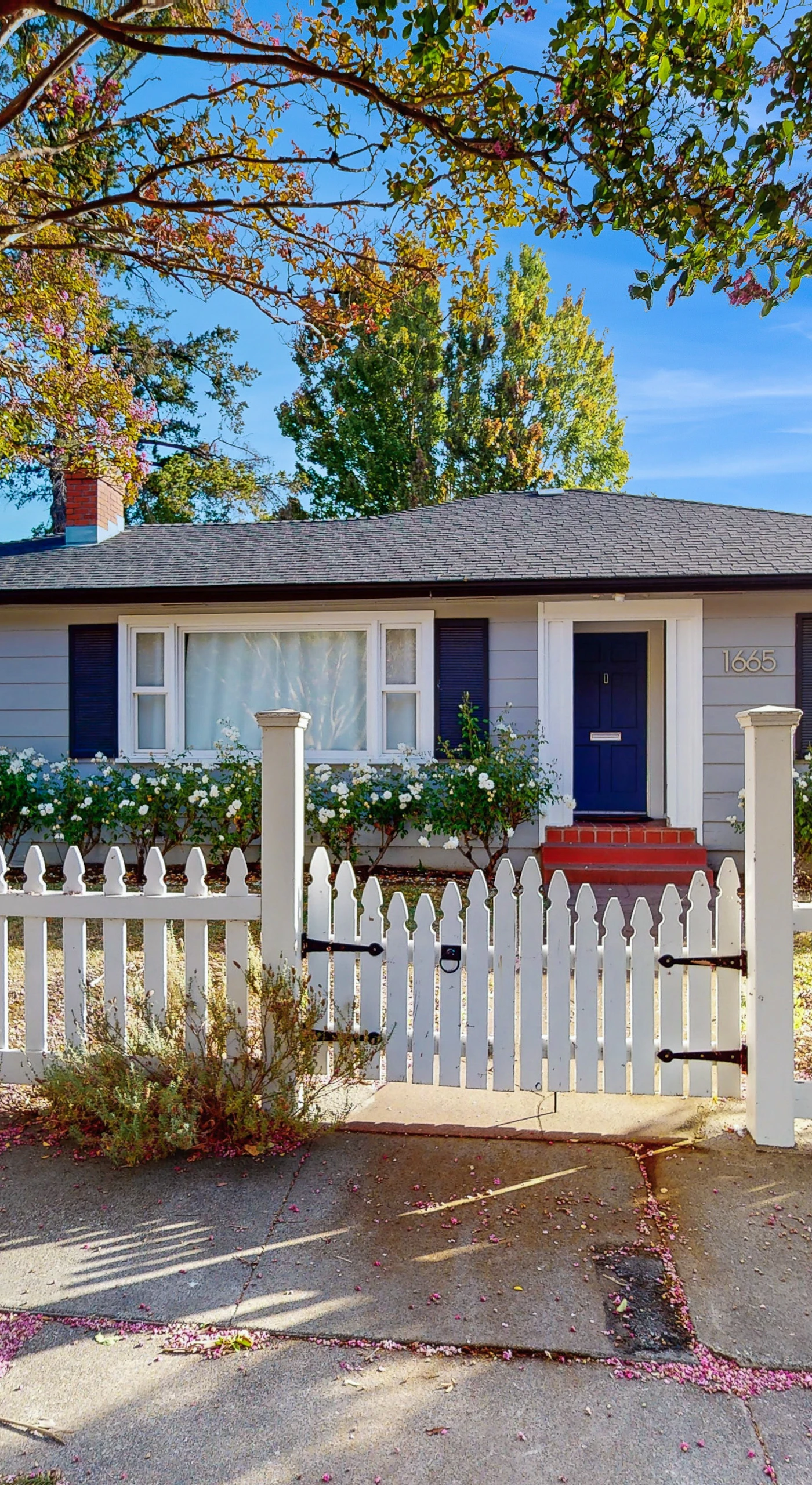 Welcome to your wine country hideaway — a charming cottage with white picket fence, flower boxes, and a private entrance tucked beneath mature shade trees in Santa Rosa