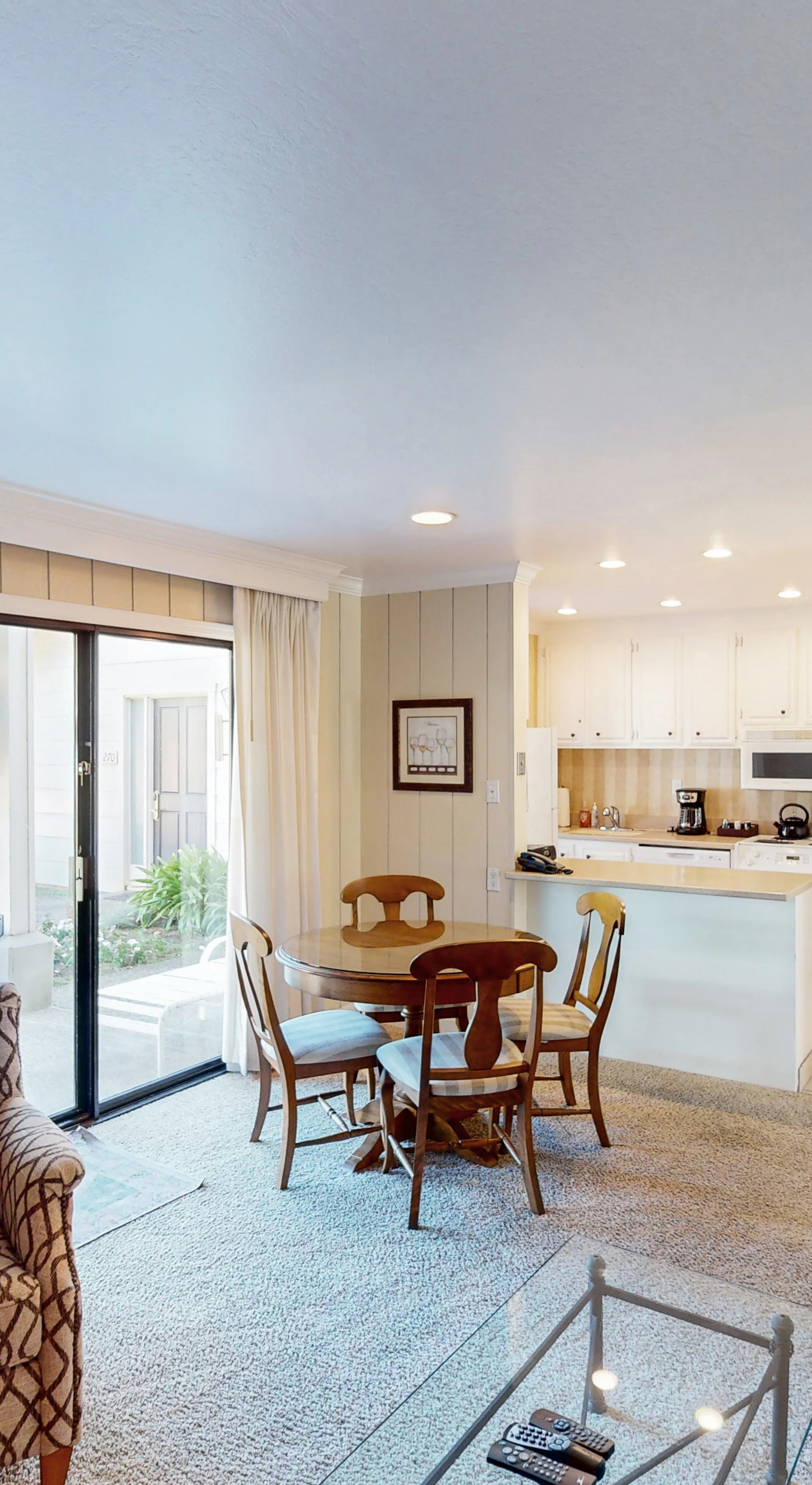 Settle into your open-concept living space with golf course views streaming through floor-to-ceiling sliders — kitchen, dining, and lounge all in one bright room.