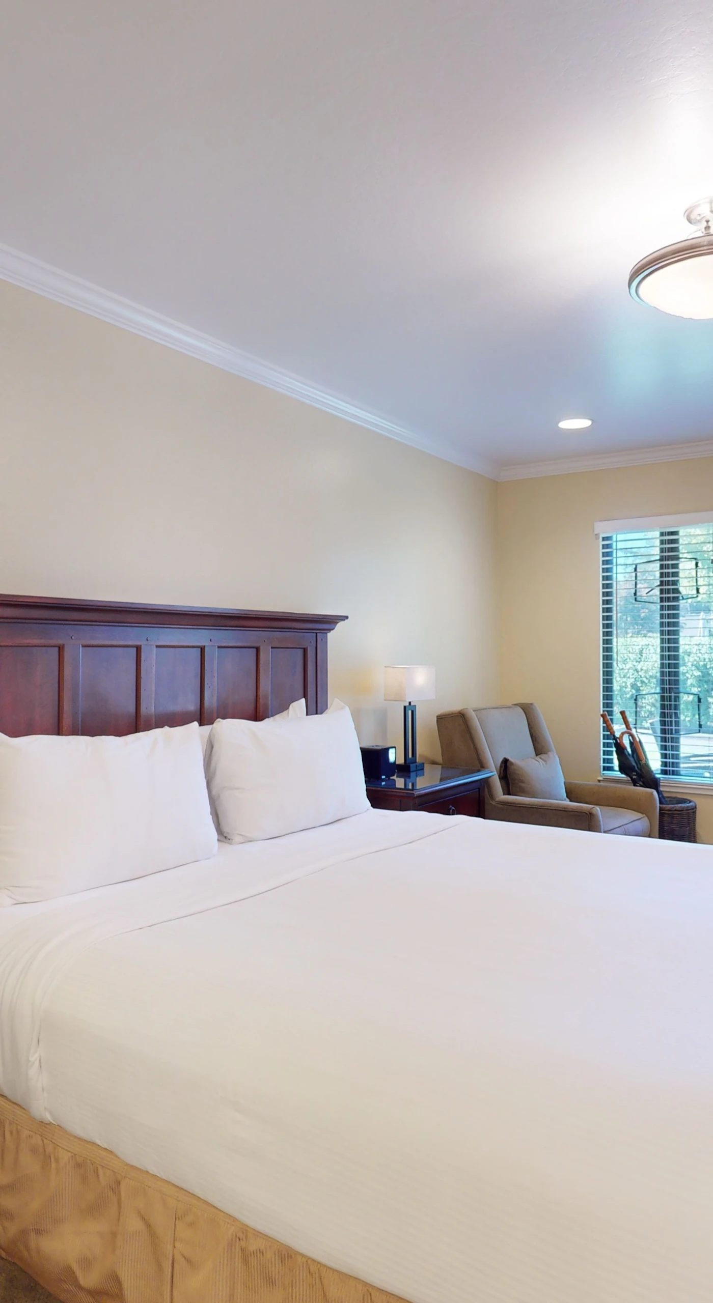 Settle into your plush king bed after a day exploring Napa Valley wineries — crisp white linens, elegant dark-wood furnishings, and soft lighting set the tone for a restful retreat.