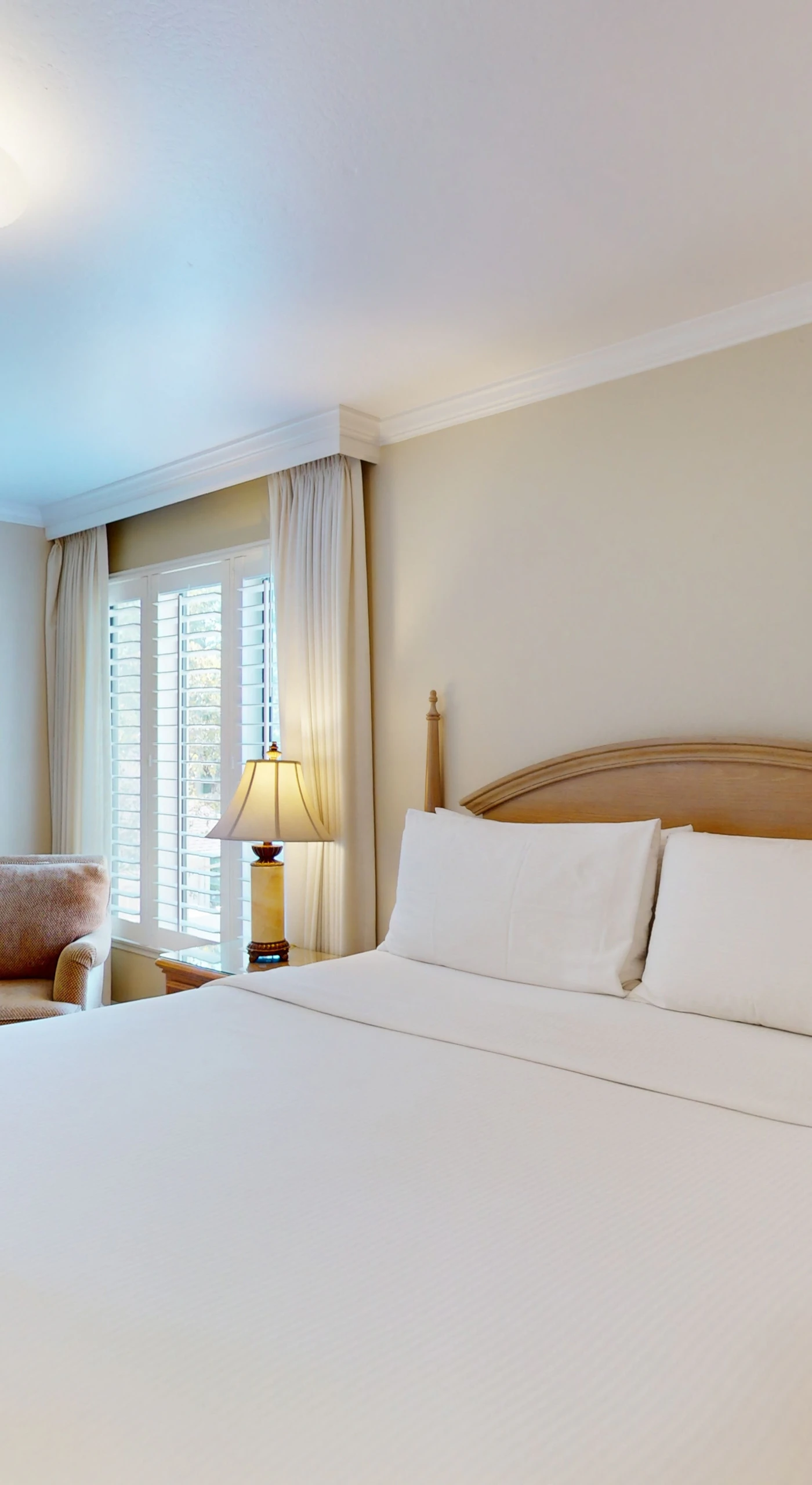 Rest your head on crisp white linens in your resort-style king bedroom — natural light filters through plantation shutters for a serene Napa morning wake-up.