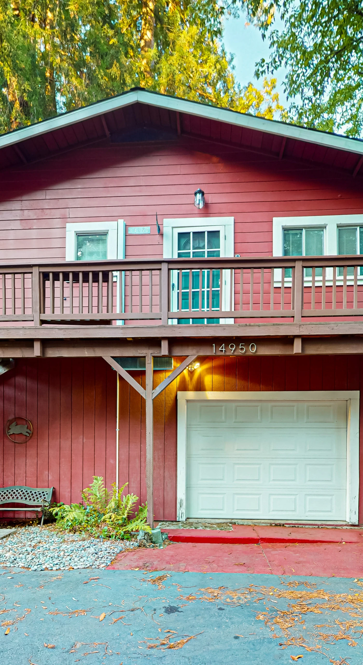 Welcome to your classic redwood-country retreat — Villa Eileen's warm red exterior, private garage, and upper deck tucked beneath towering trees.