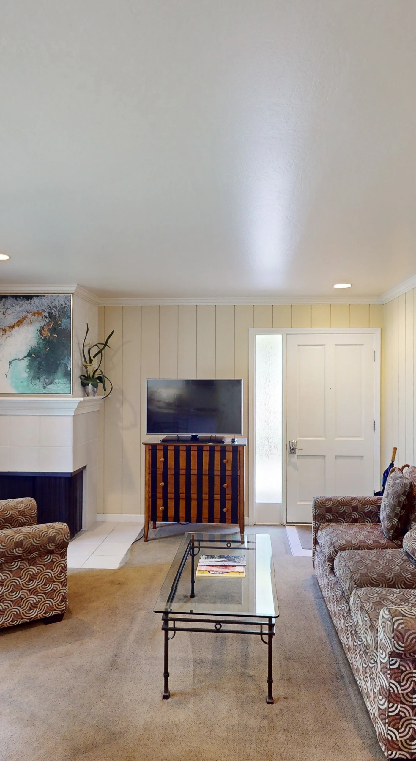 Relax in your stylishly appointed Napa condo living room featuring comfortable seating for four, a large flat-screen TV, and natural light streaming through the glass patio door.