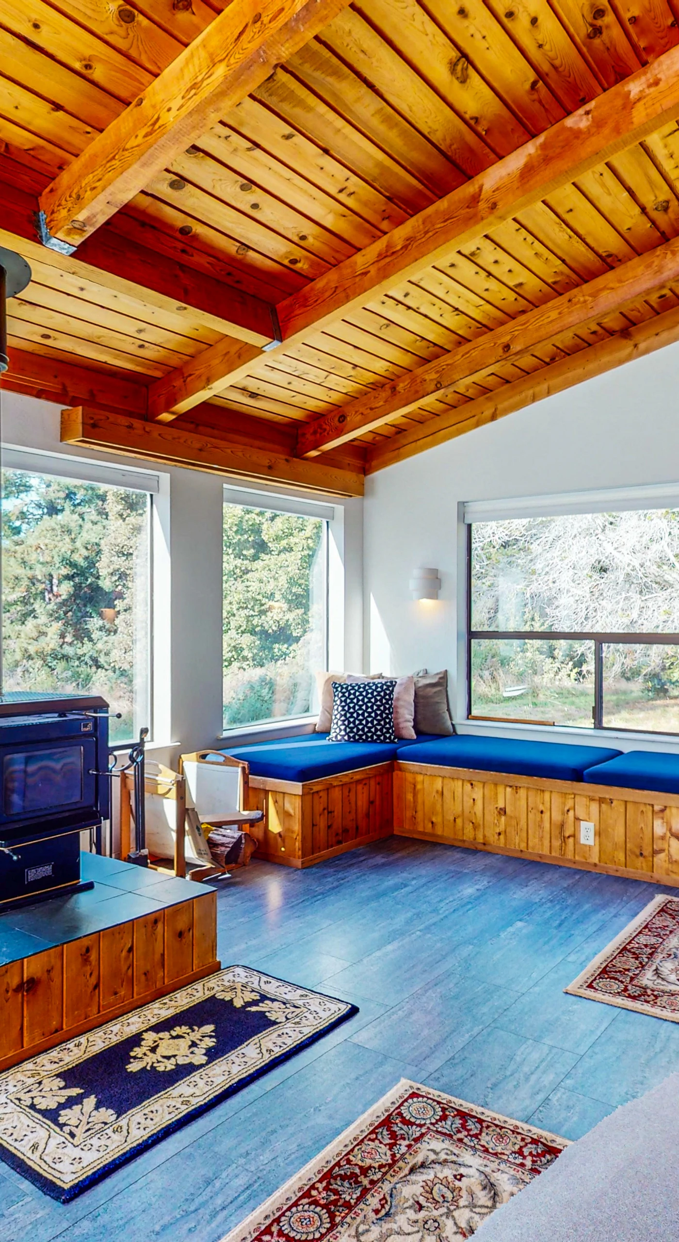 Gather around the cozy fireplace in the living room, where natural light filters through expansive windows, inviting warmth and relaxation.