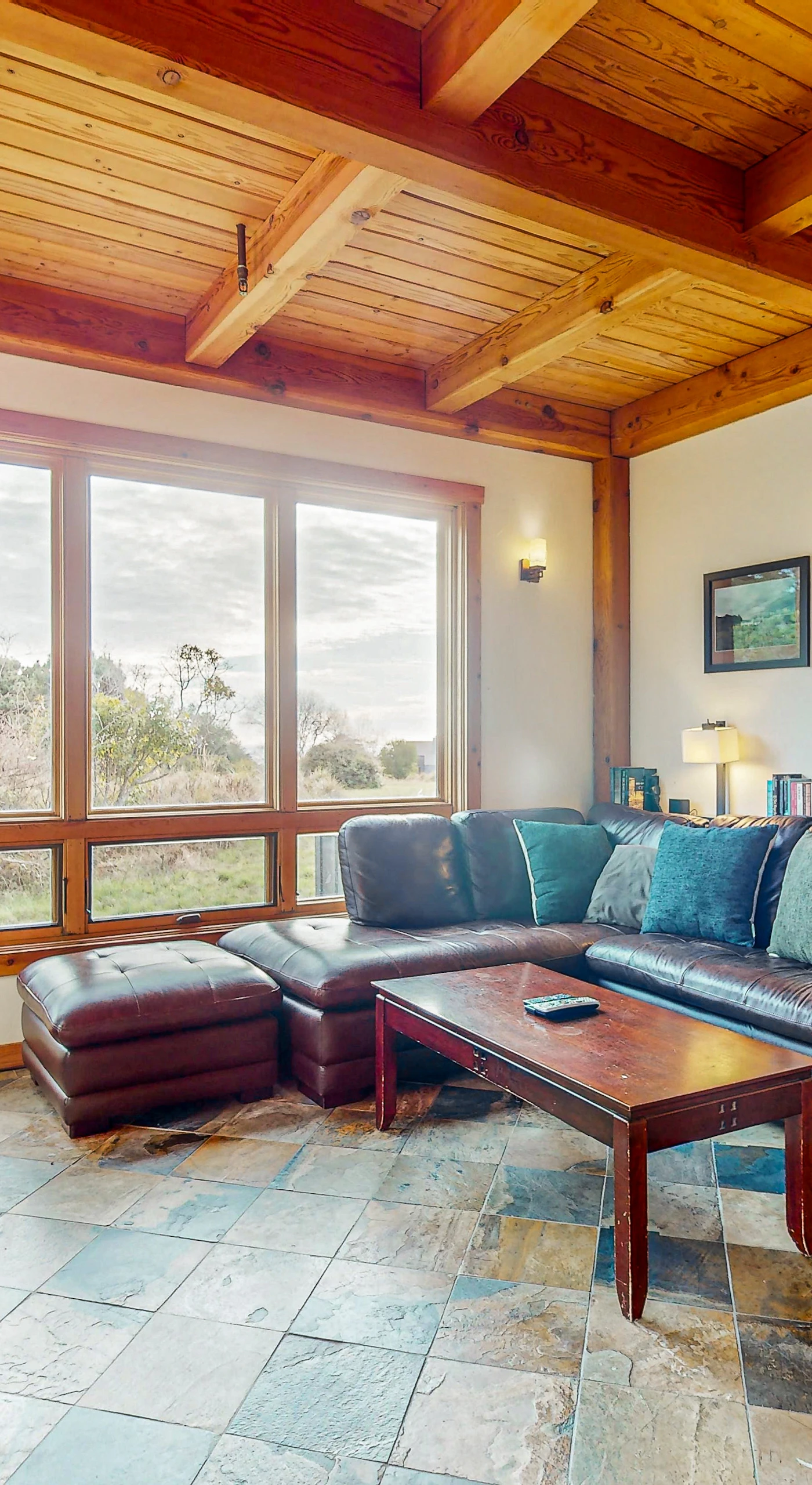 Gather around the warmth of the gas fireplace in this inviting living room, where natural light dances off the wood beams and offers views of the serene landscape.