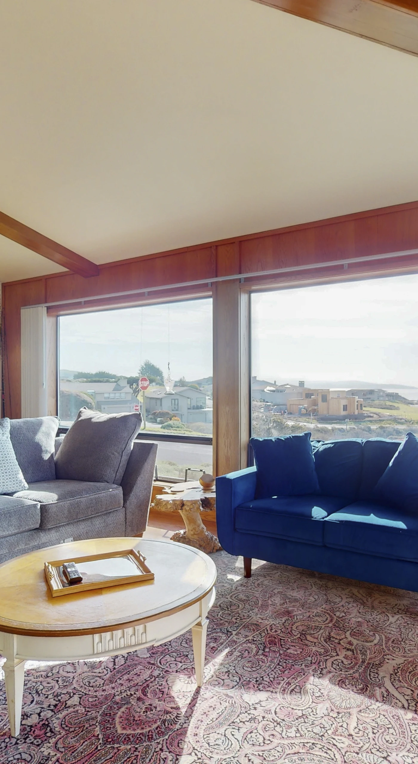 Sink into plush sofas and gaze out at Bodega Bay through panoramic windows in your sun-drenched coastal living room with vaulted beam ceilings
