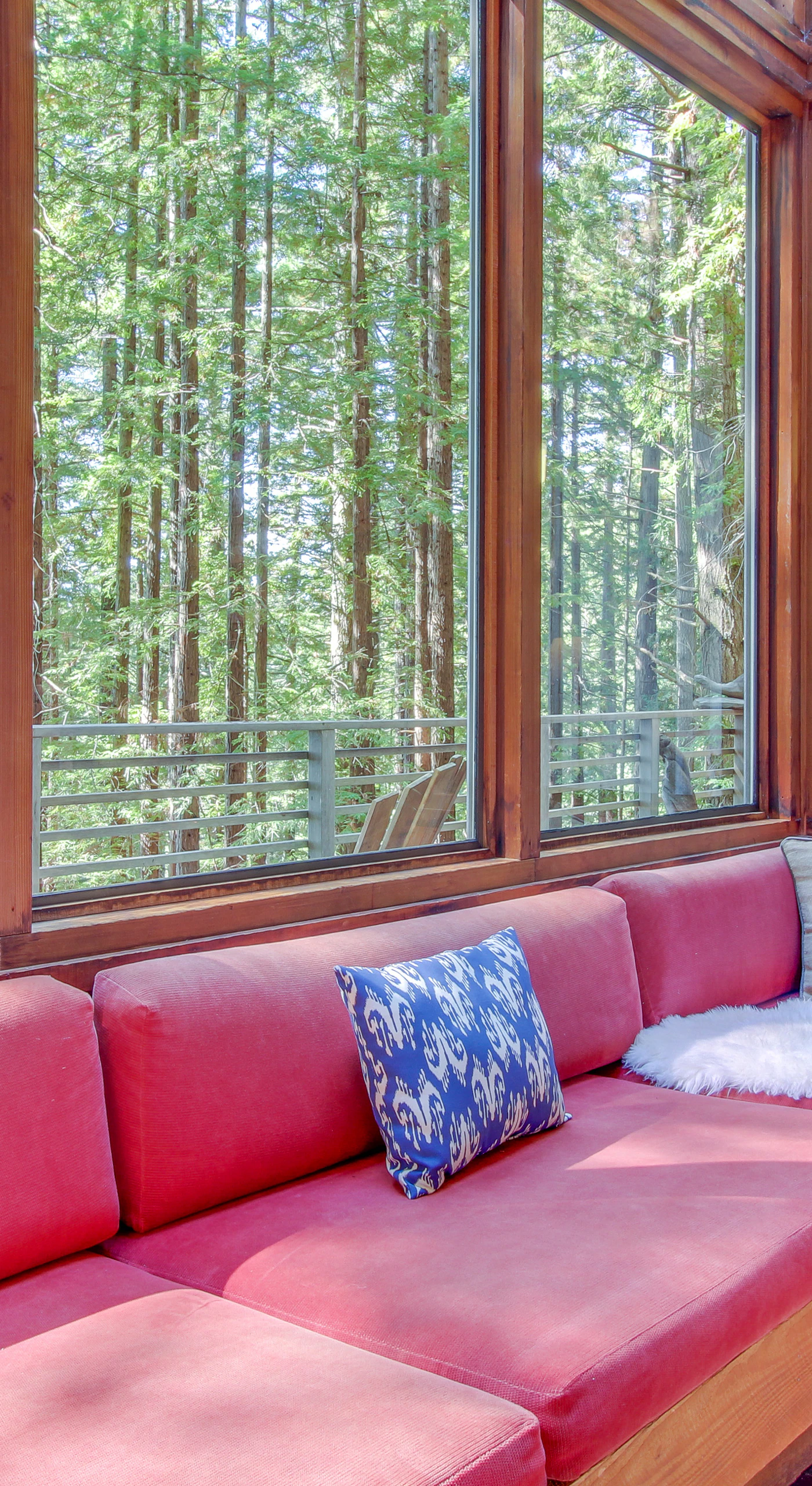 Curl up on the plush red sofa, where you can lose yourself in a good book while enjoying the lush forest views.