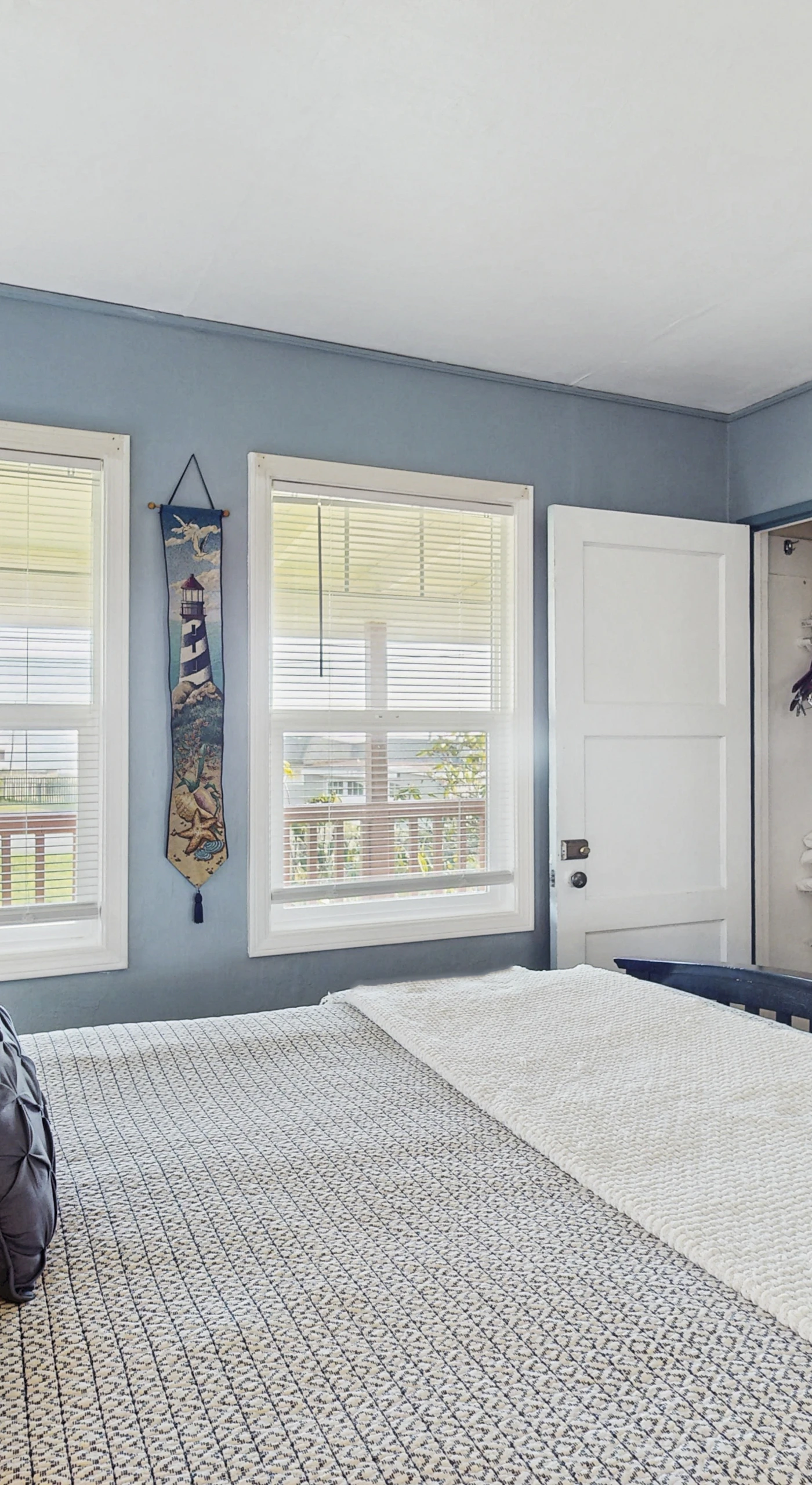 Step from your seaside-blue bedroom directly onto the deck through a private door — the wall-mounted TV and dark-wood dresser keep your retreat both stylish and functional.