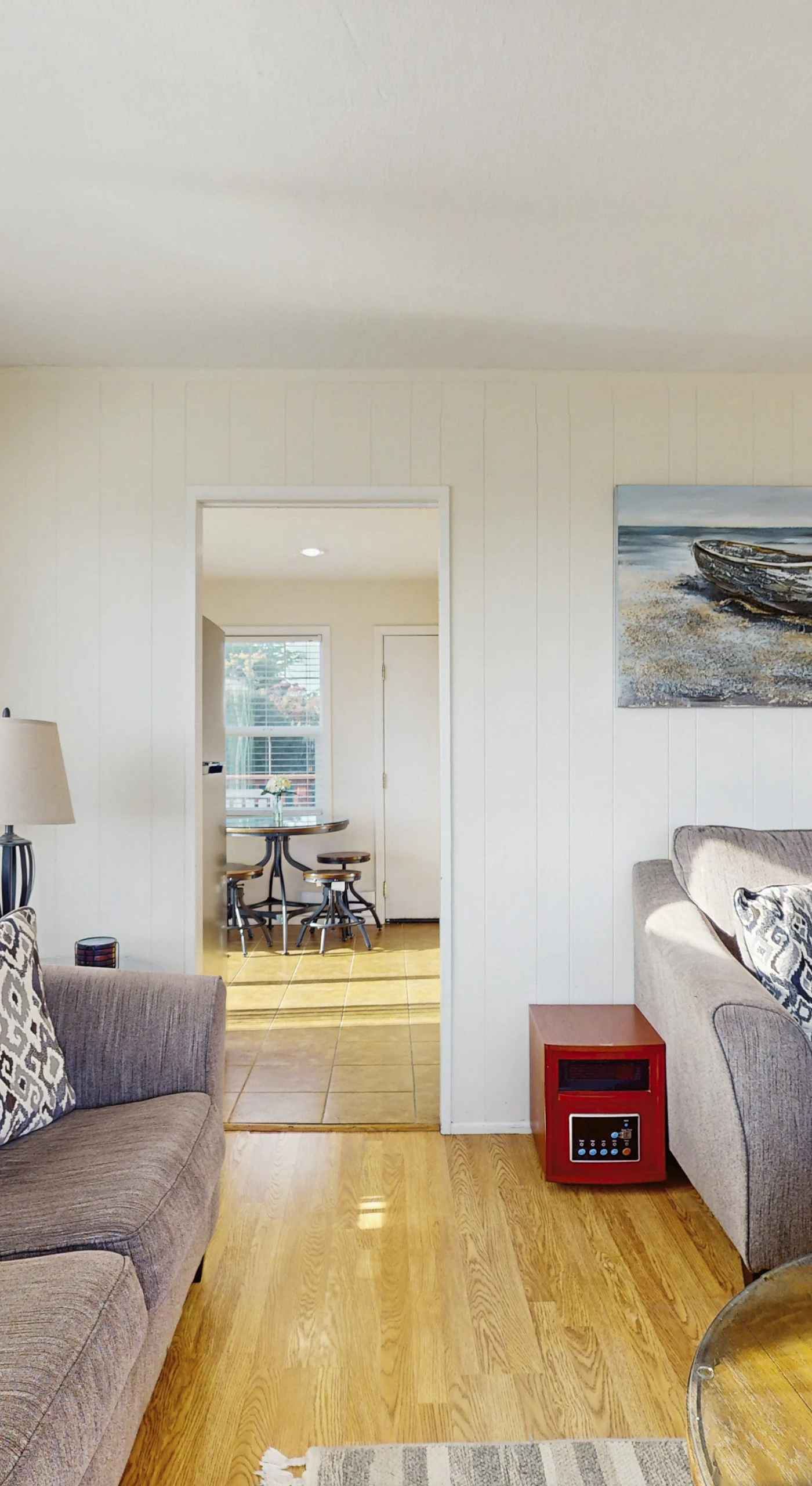 Let natural light pour through sliding glass doors as you relax among coastal artwork and warm hardwood floors — your gateway to the deck is just steps away.
