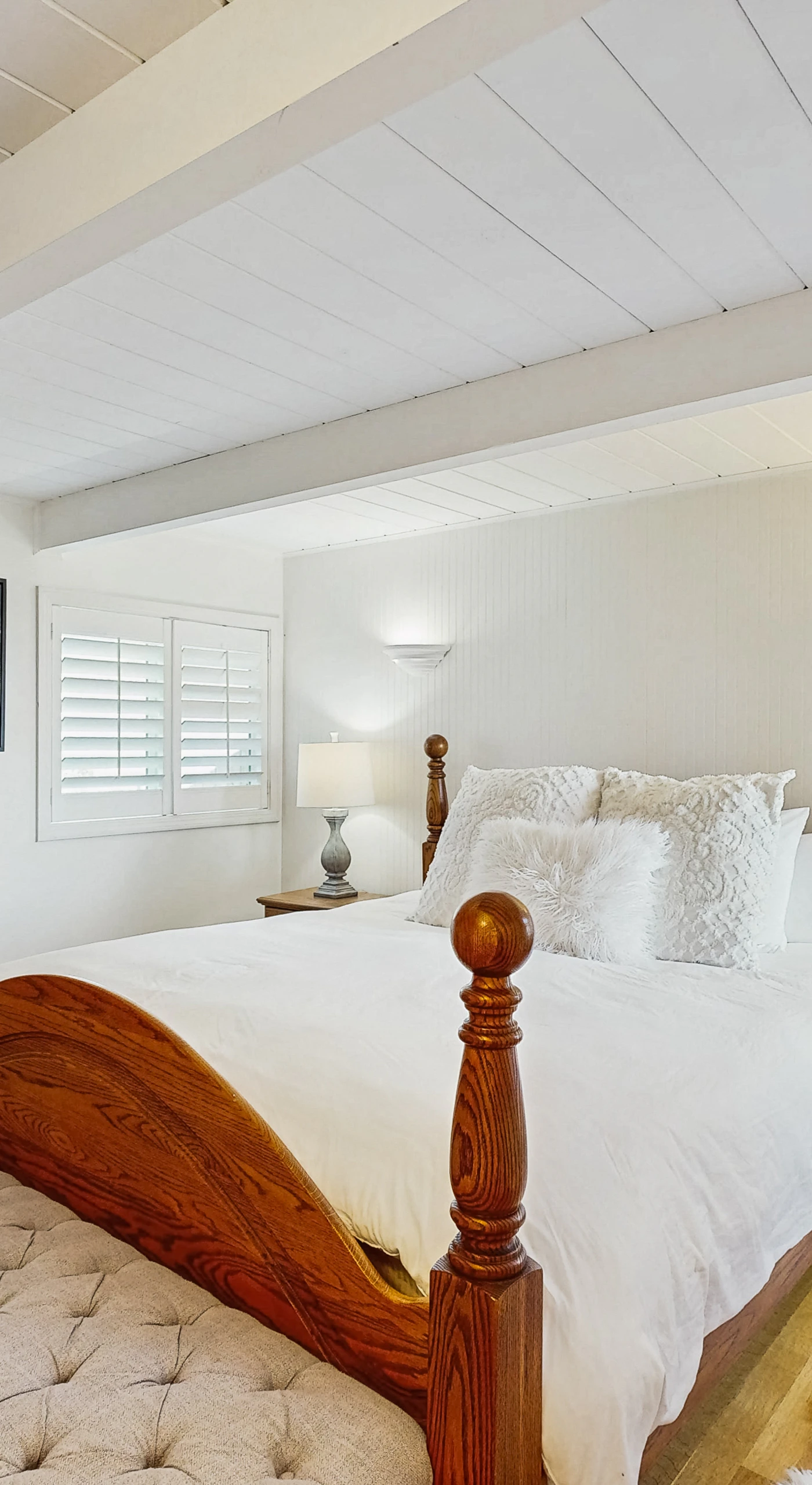Rest in your serene primary bedroom with elegant four-poster bed, flat-screen TV, and hardwood floors