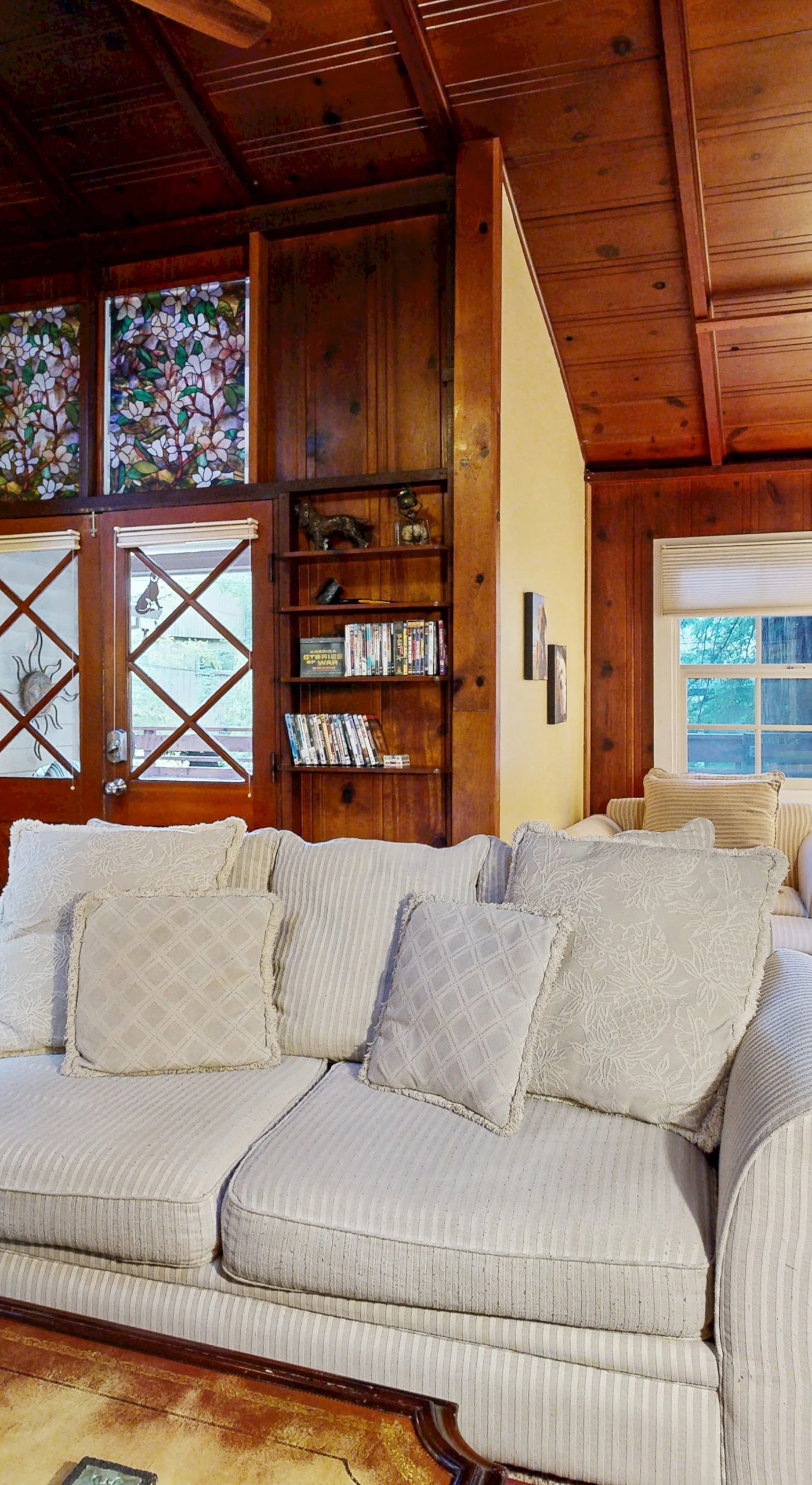 Charming wood-paneled walls and a glass-front bookcase give your living space a warm, cabin-inspired redwood retreat feel.